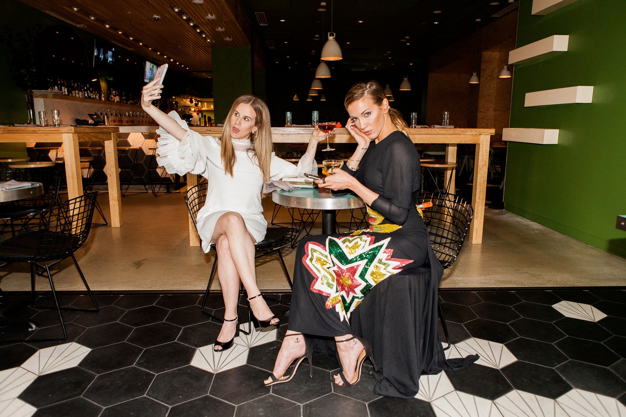 Katie Cassidy takes a selfie with a friend at a restaurant HD Wallpaper