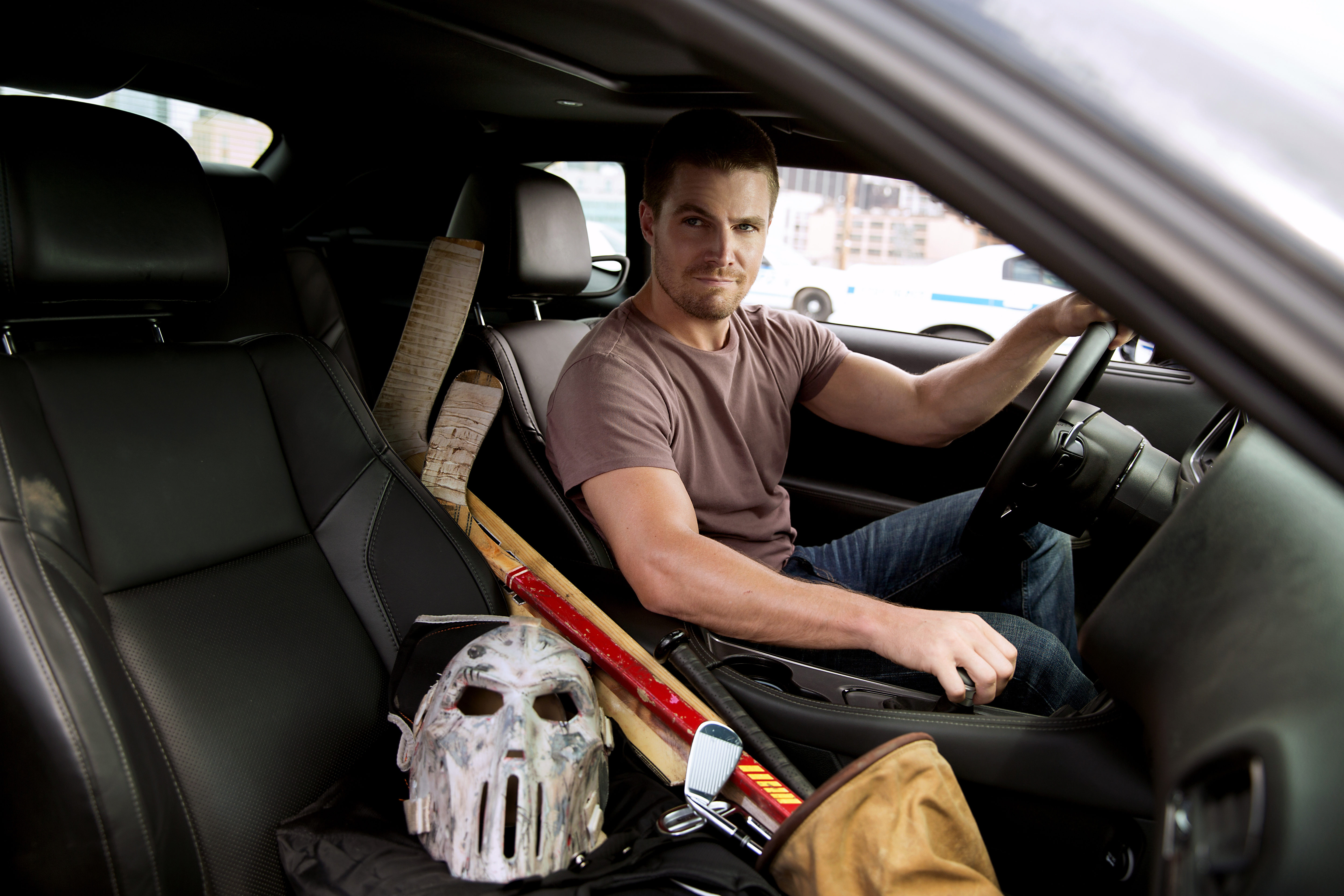 Stephen Amell in a car with hockey sticks and a mask HD Wallpaper