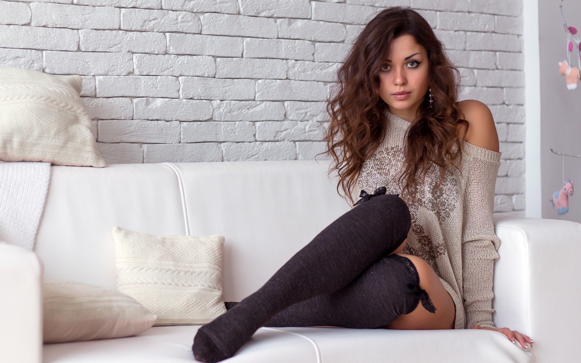 Woman in sweater and thigh-high socks on couch HD Wallpaper