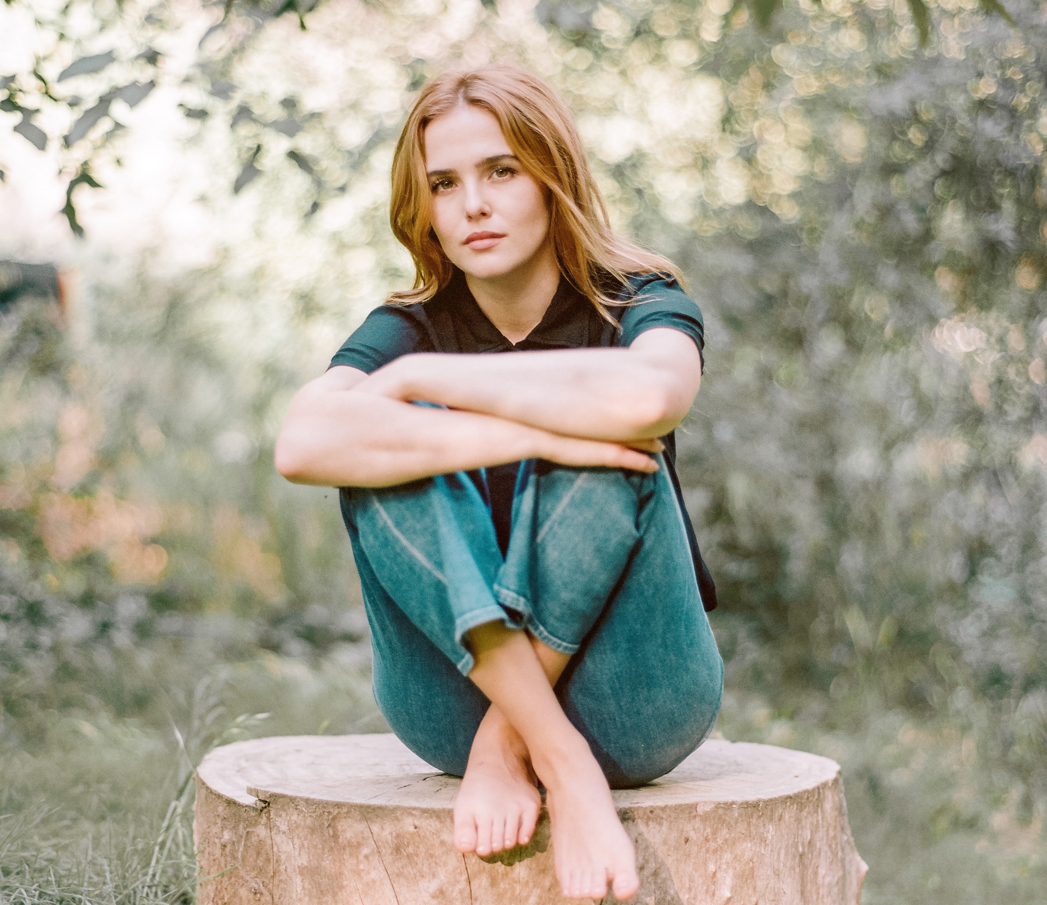 Zoey Deutch sitting on a tree stump HD Wallpaper