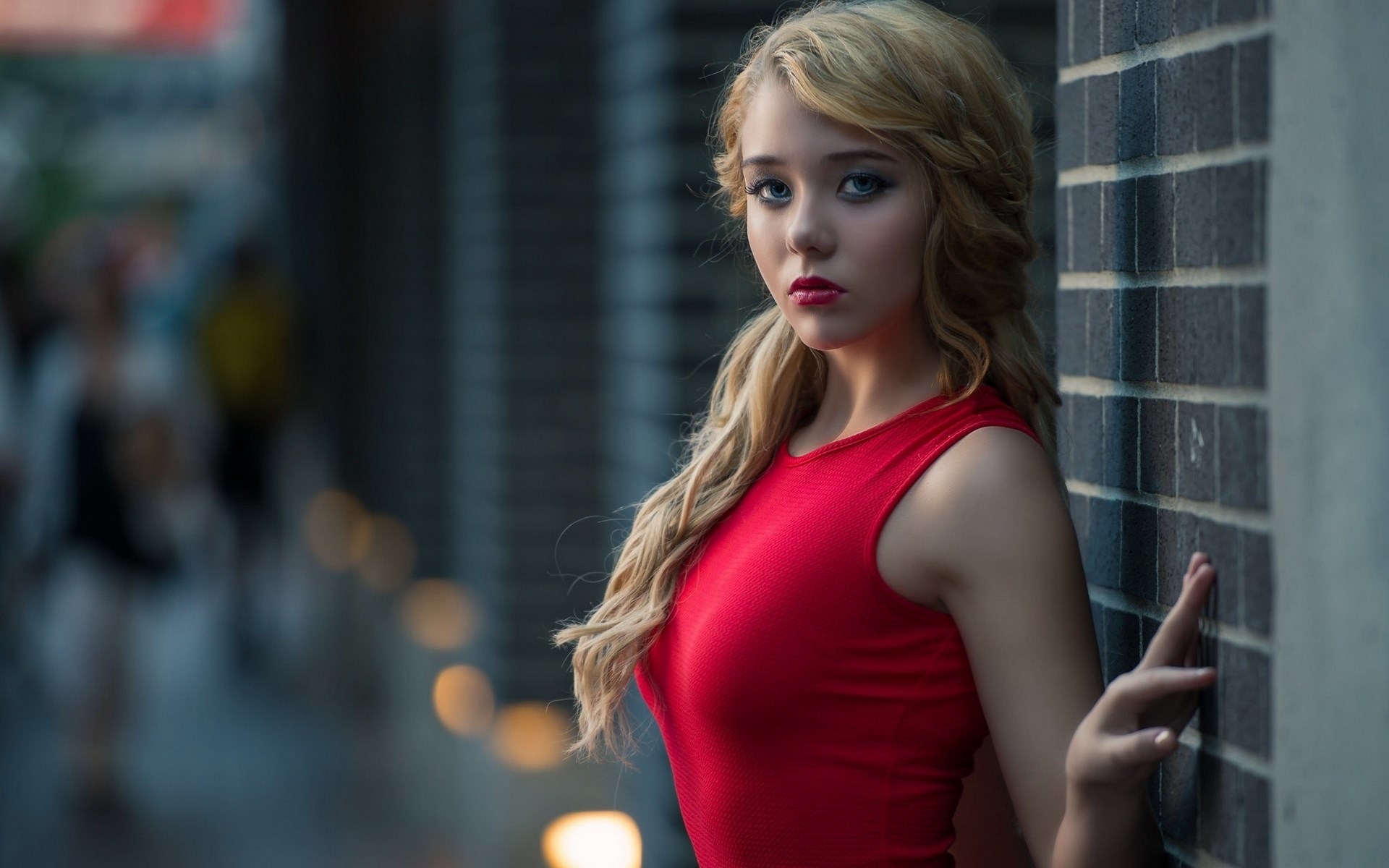 Young woman in red dress leaning against brick wall HD Wallpaper