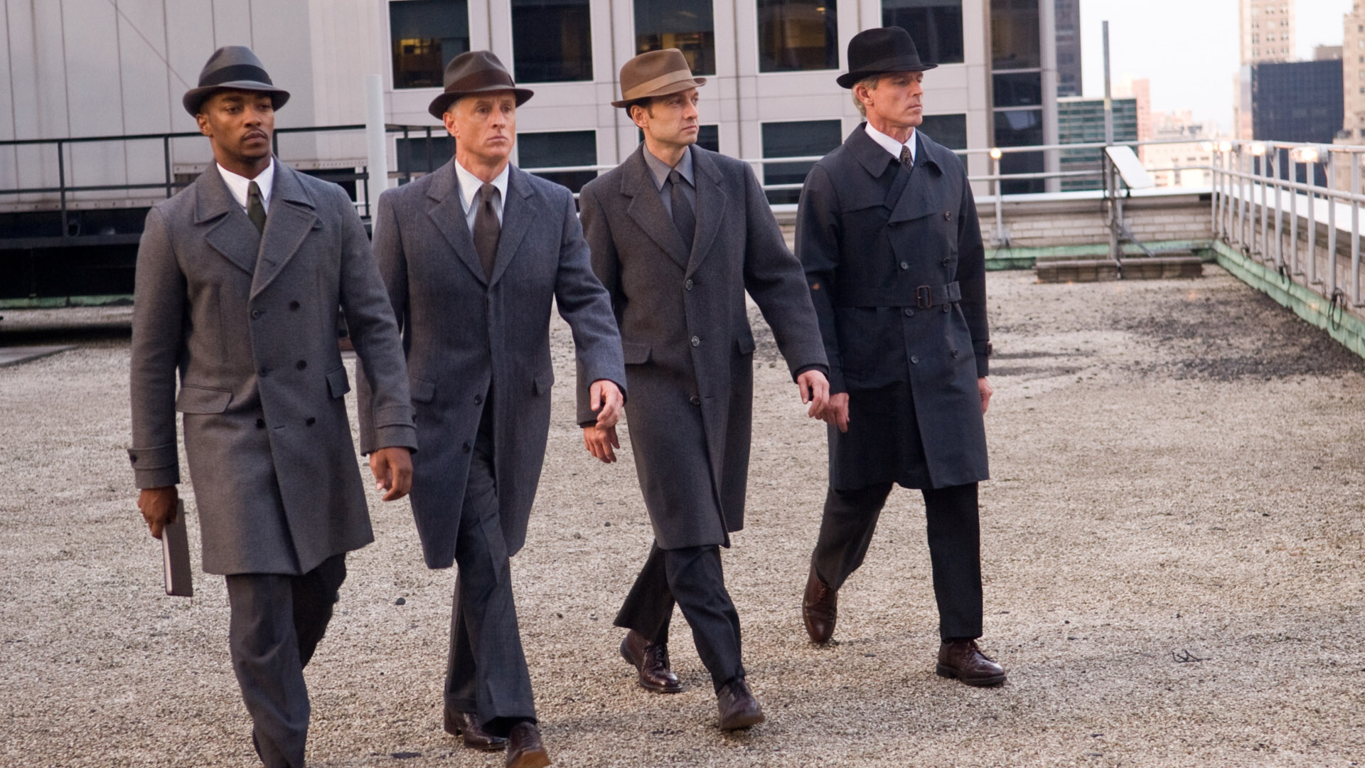Four men in fedoras and trench coats walking on a rooftop HD Wallpaper