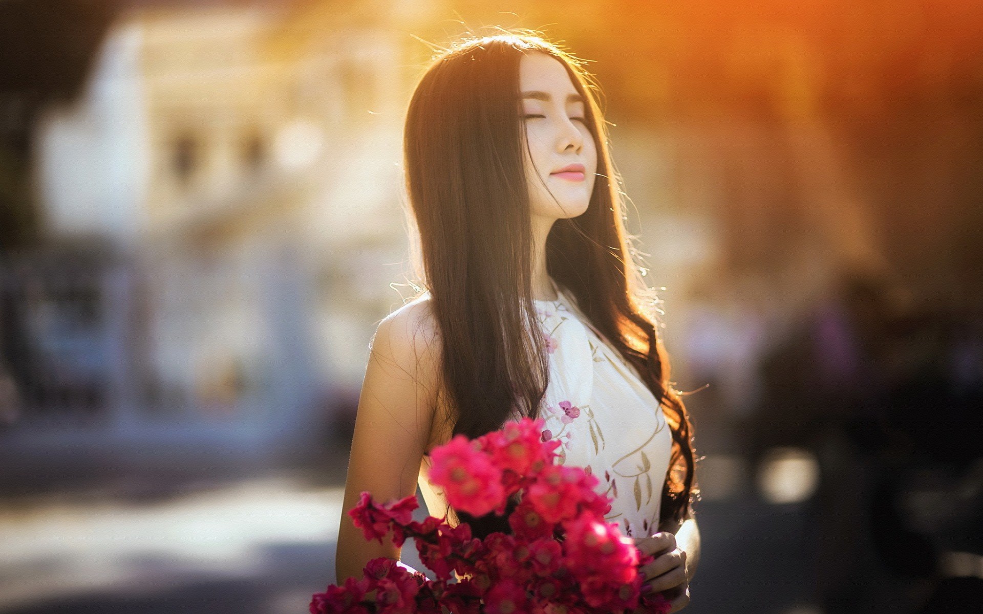 Woman holding pink flowers in sunlight HD Wallpaper