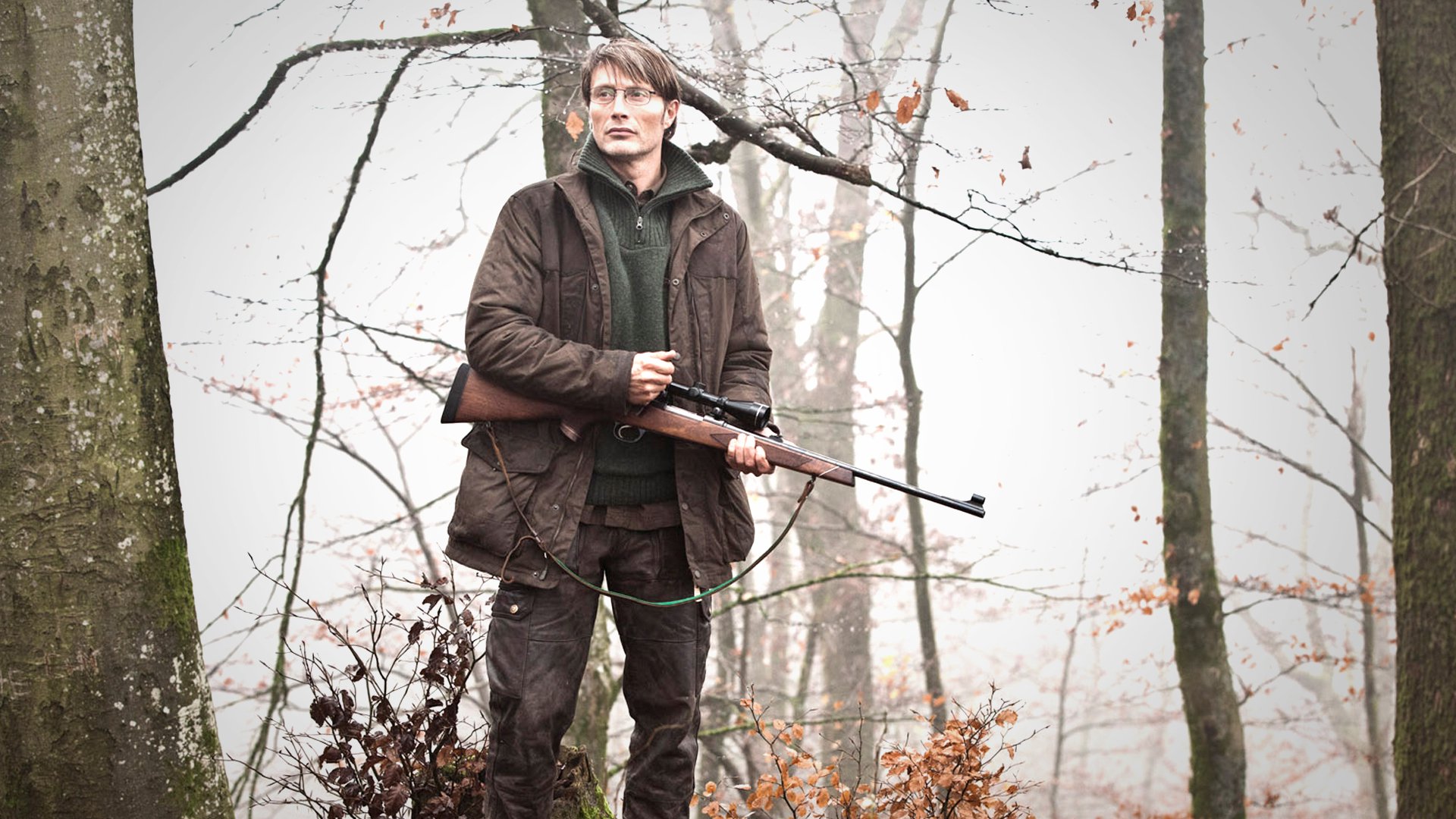 Mads Mikkelsen with a rifle in a forest HD Wallpaper