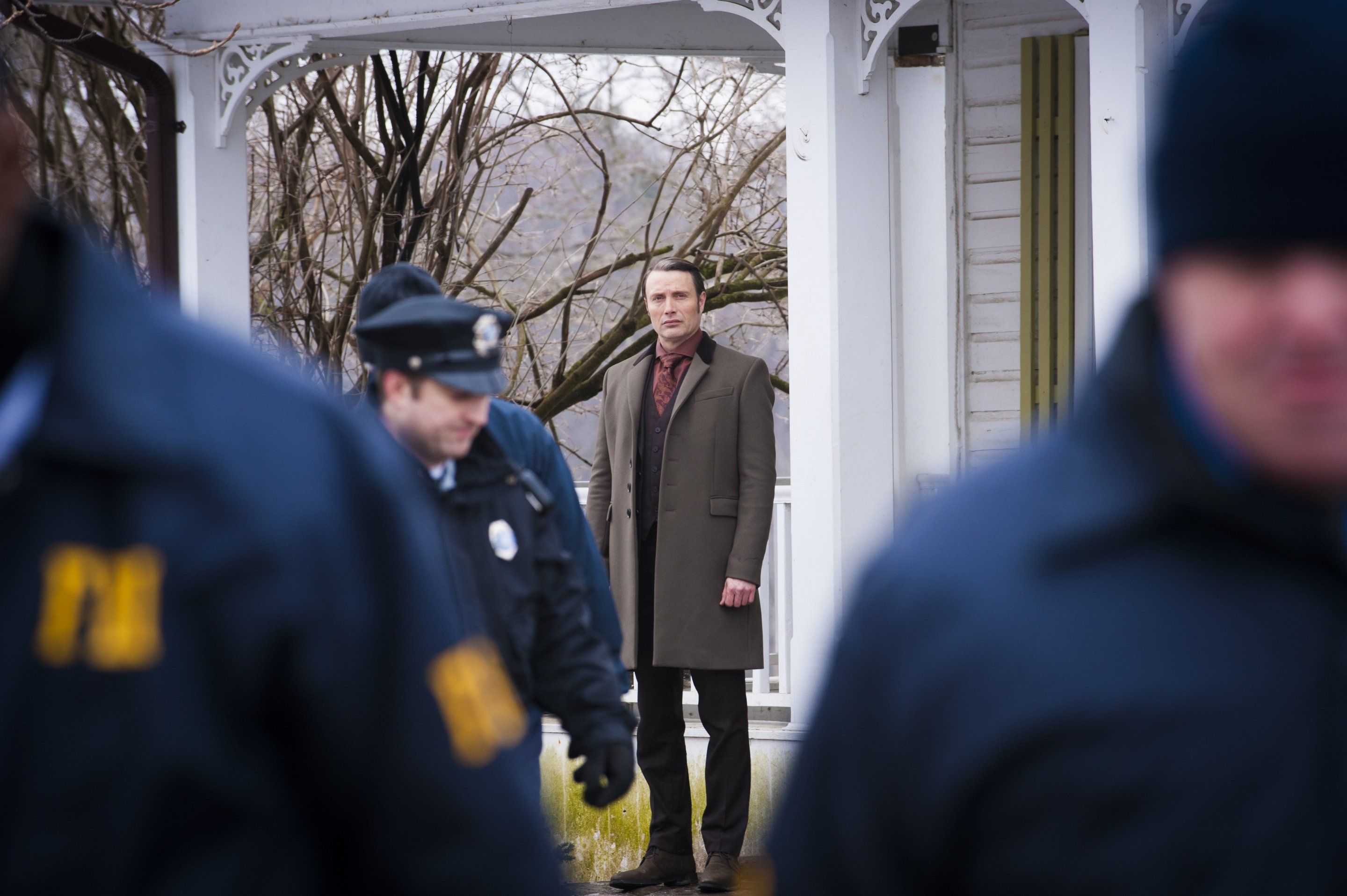 Mads Mikkelsen in a coat standing outside a house HD Wallpaper