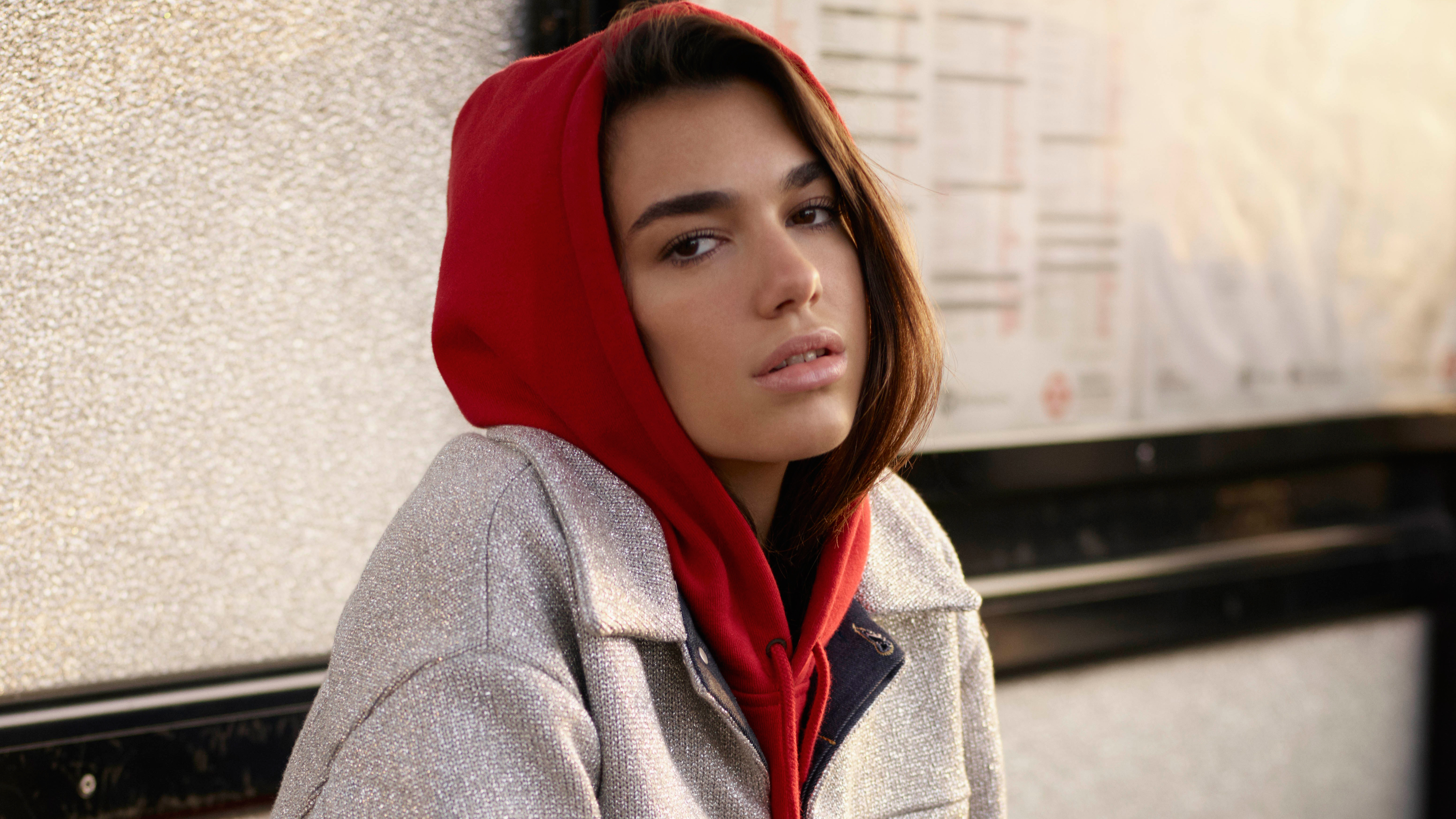 Dua Lipa wearing a red hoodie and silver jacket HD Wallpaper