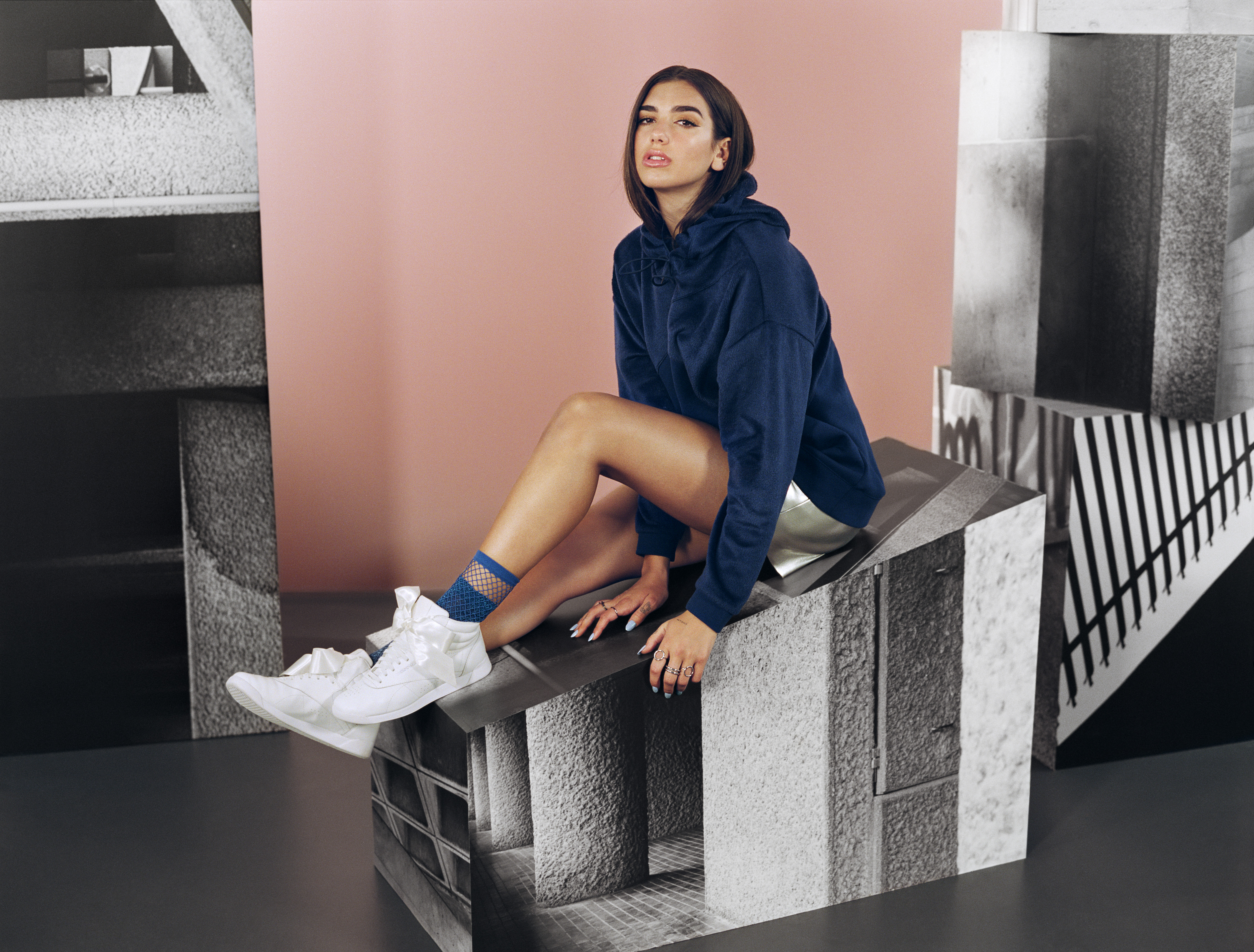 Dua Lipa sitting on a geometric structure HD Wallpaper