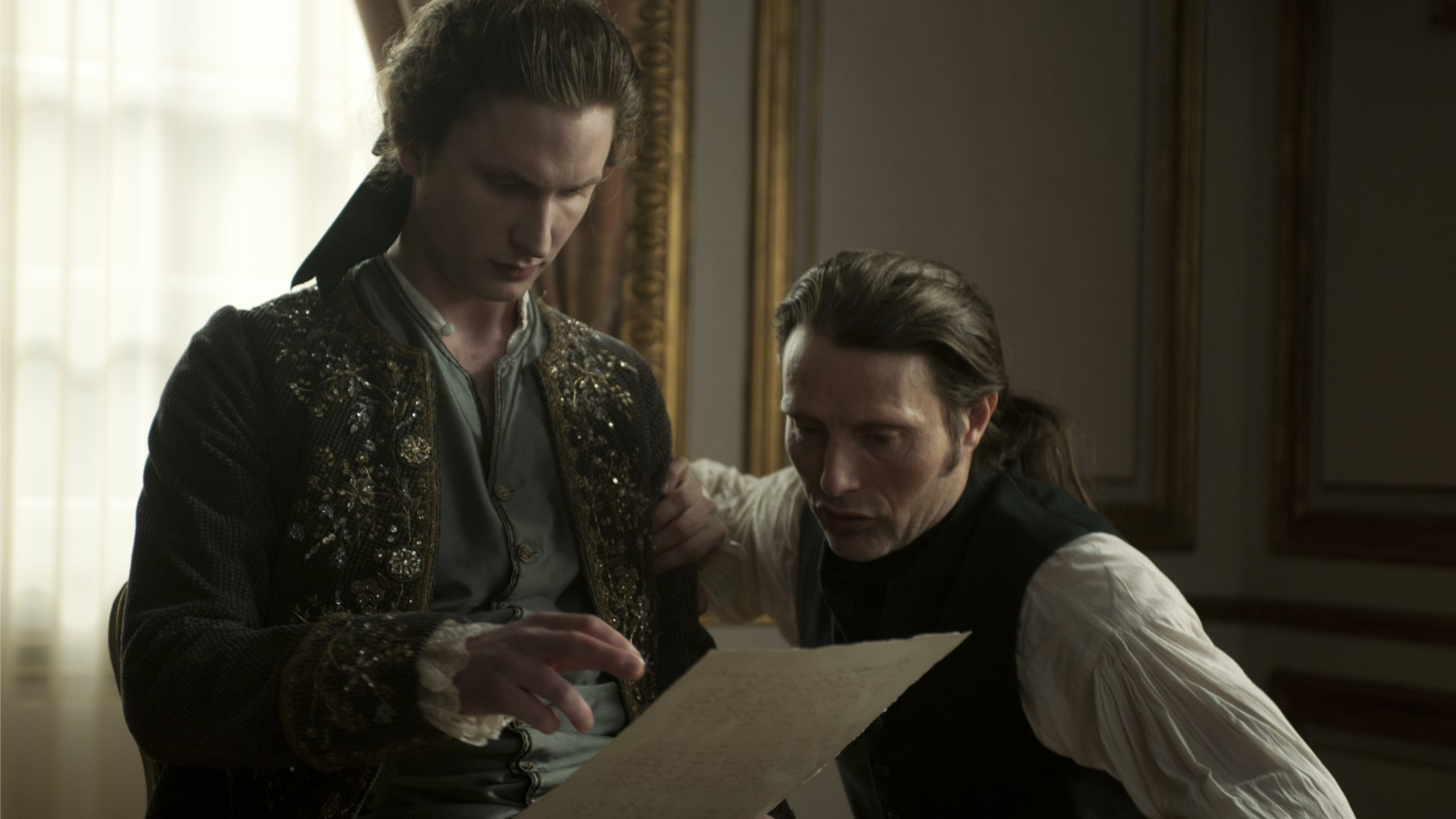 Mads Mikkelsen and man in historical attire looking at paper HD Wallpaper