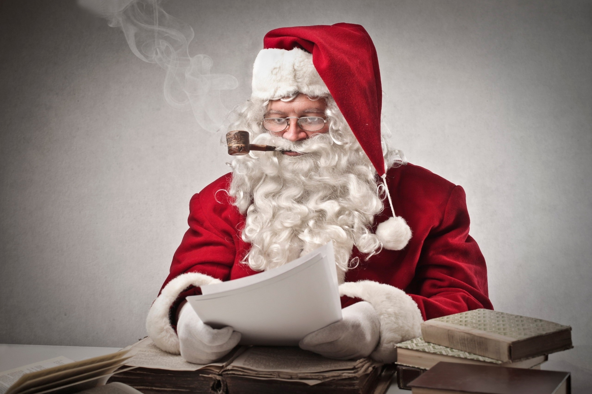 Santa Claus smoking a pipe and reading papers HD Wallpaper