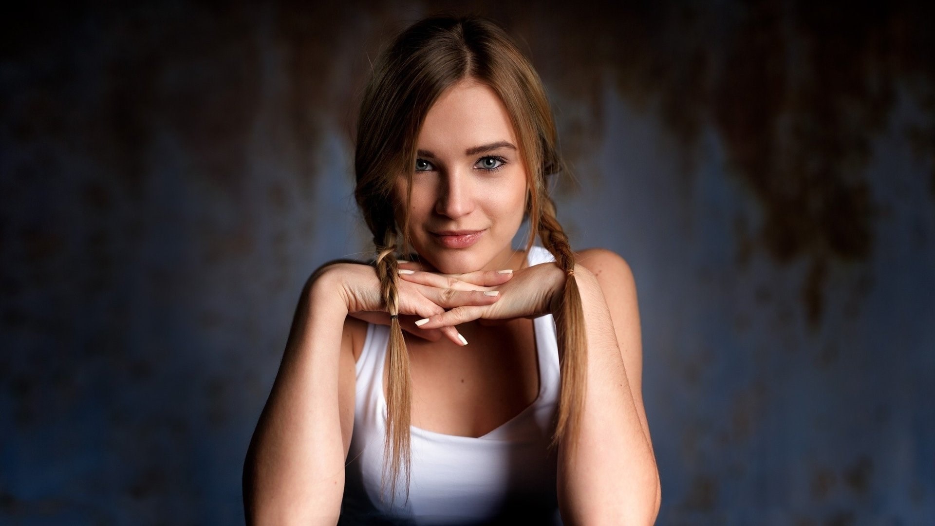 Woman with pigtails resting chin on hands HD Wallpaper