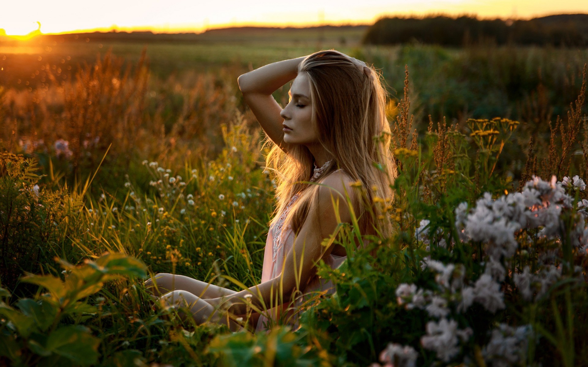 Woman sitting in a field at sunset HD Wallpaper