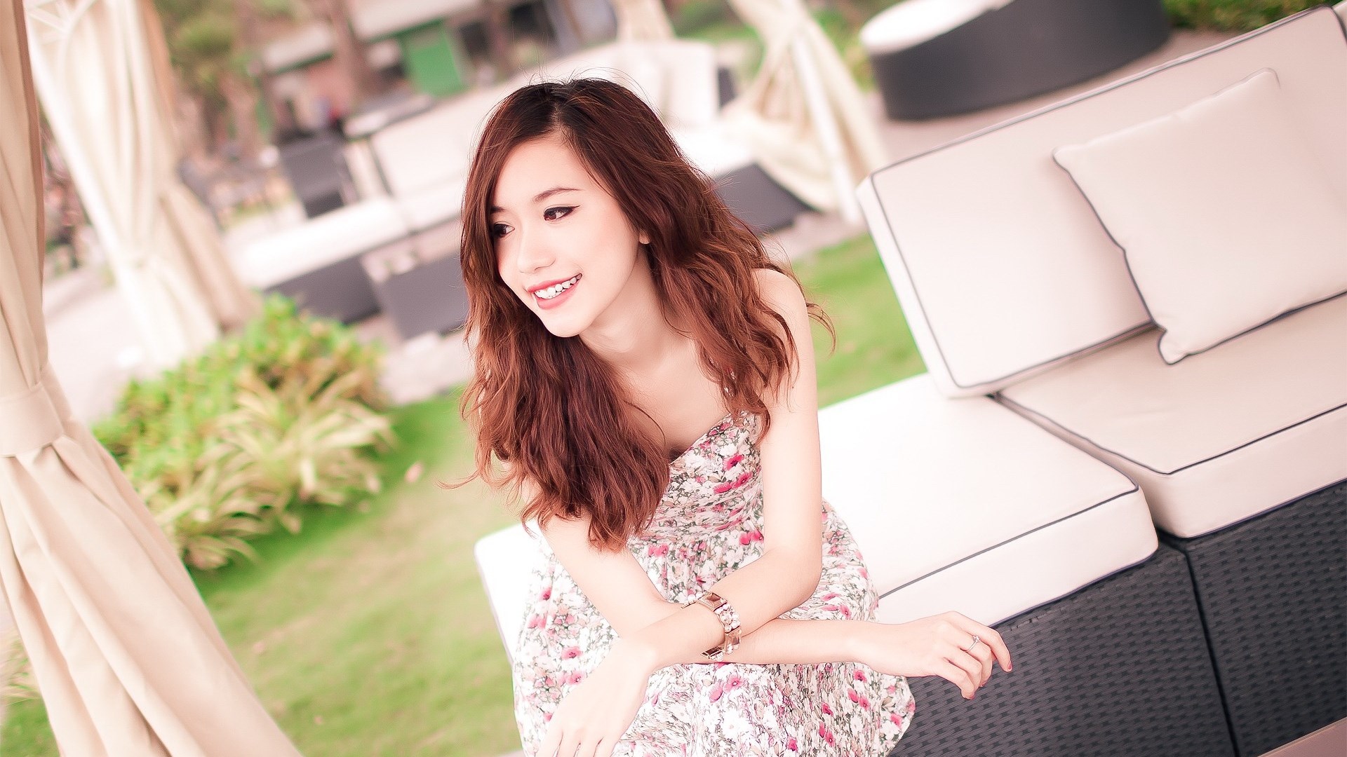 Woman in floral dress sitting on outdoor sofa HD Wallpaper