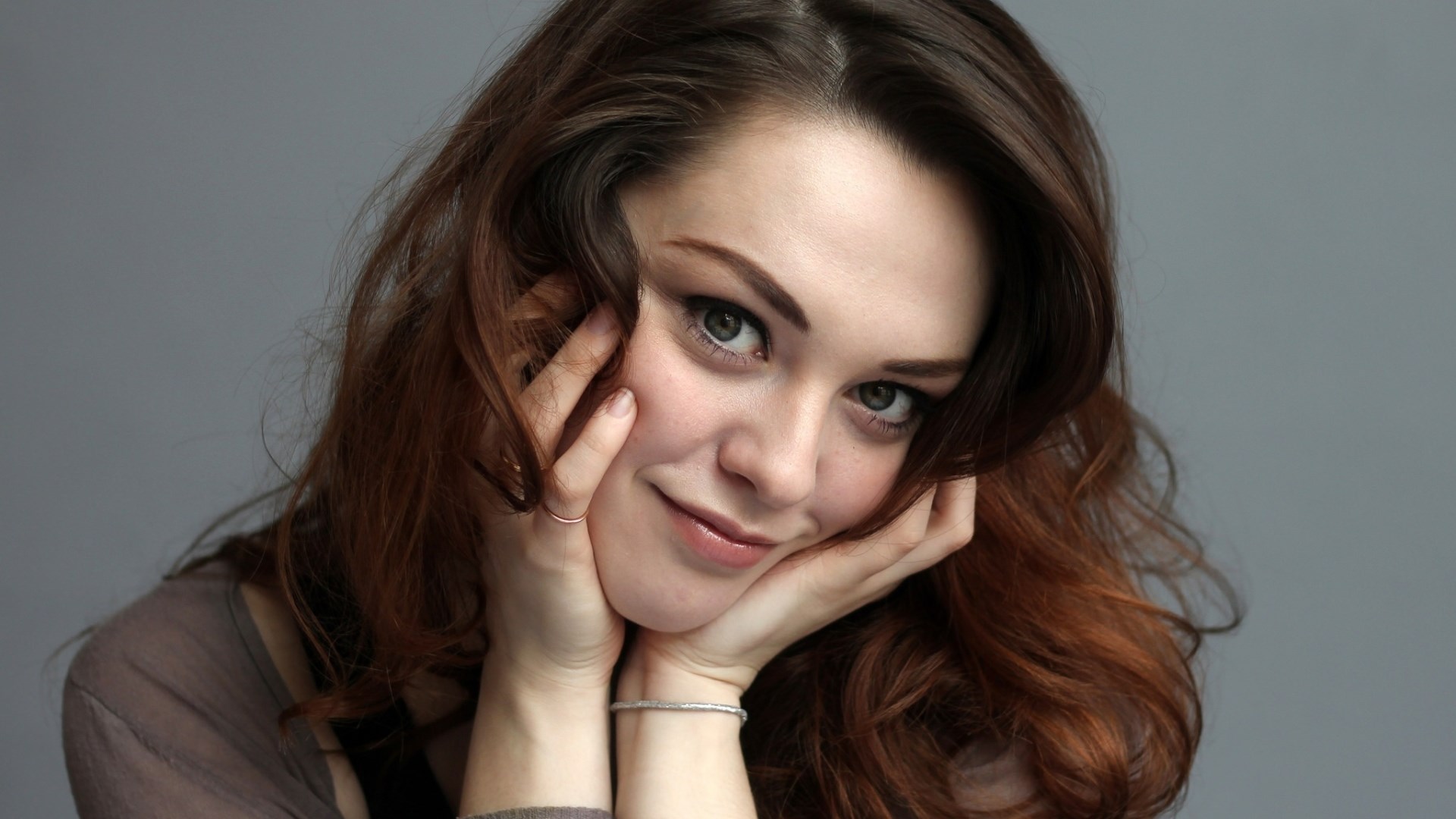 Woman with brown hair resting her face on hands HD Wallpaper