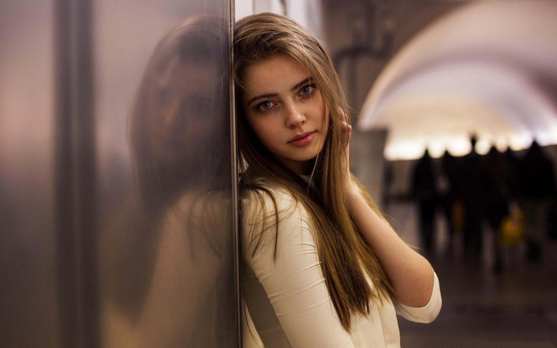 Young woman leaning against a wall in a subway station HD Wallpaper
