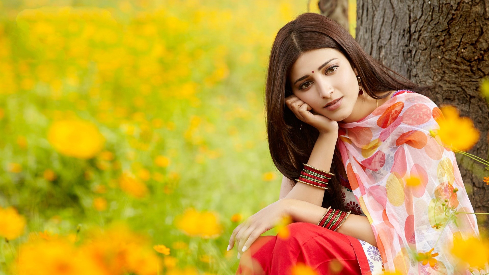 Shruti Haasan sitting in a field of yellow flowers HD Wallpaper