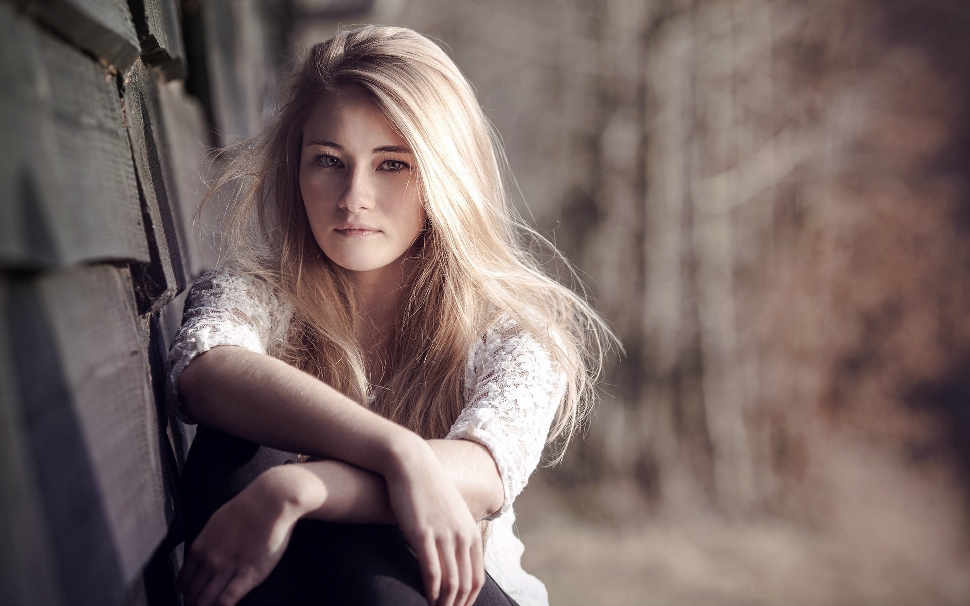 Young woman with blonde hair sitting outdoors HD Wallpaper