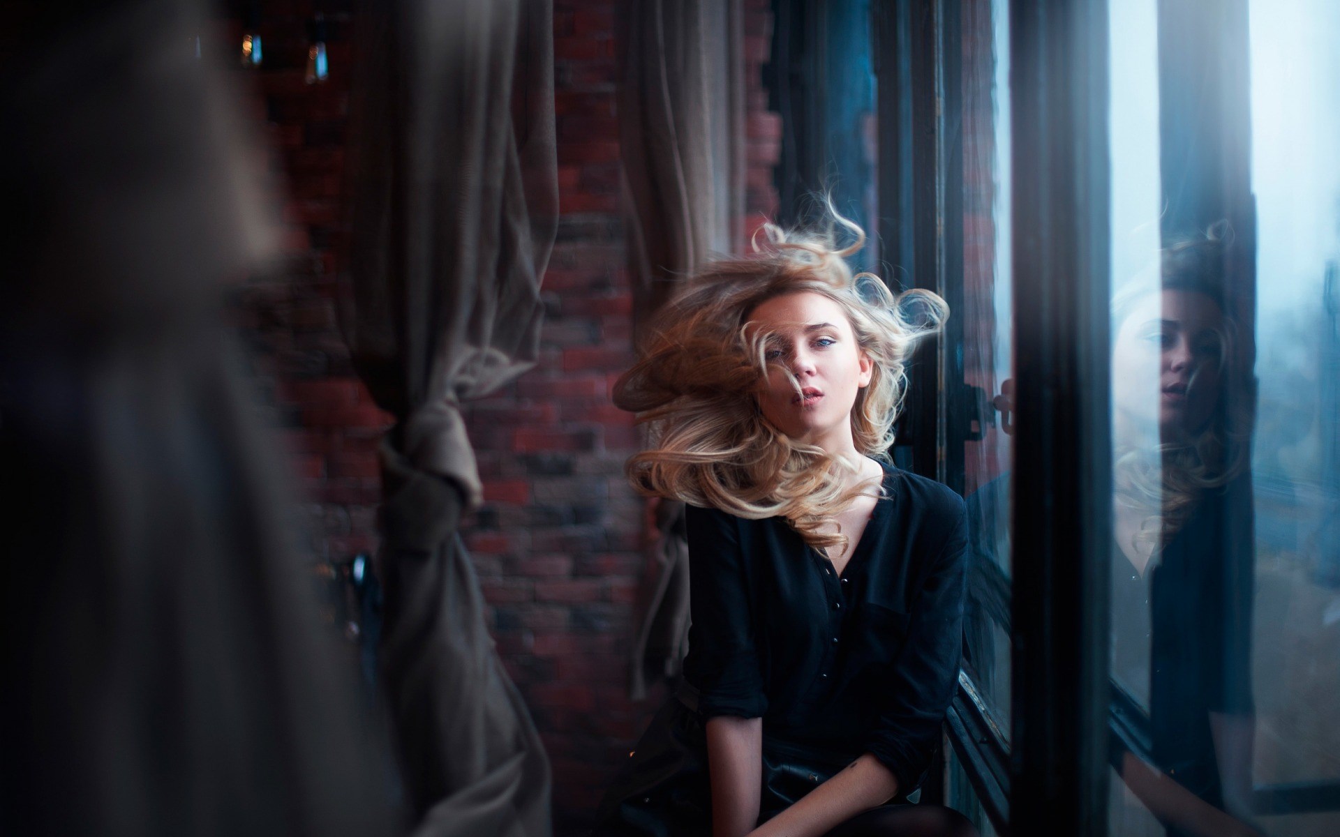 Woman with windblown hair by a window HD Wallpaper