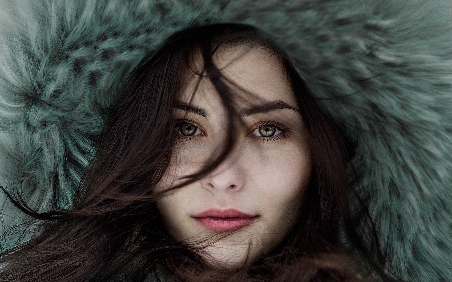 Woman with dark hair and green eyes wearing a fur hood HD Wallpaper
