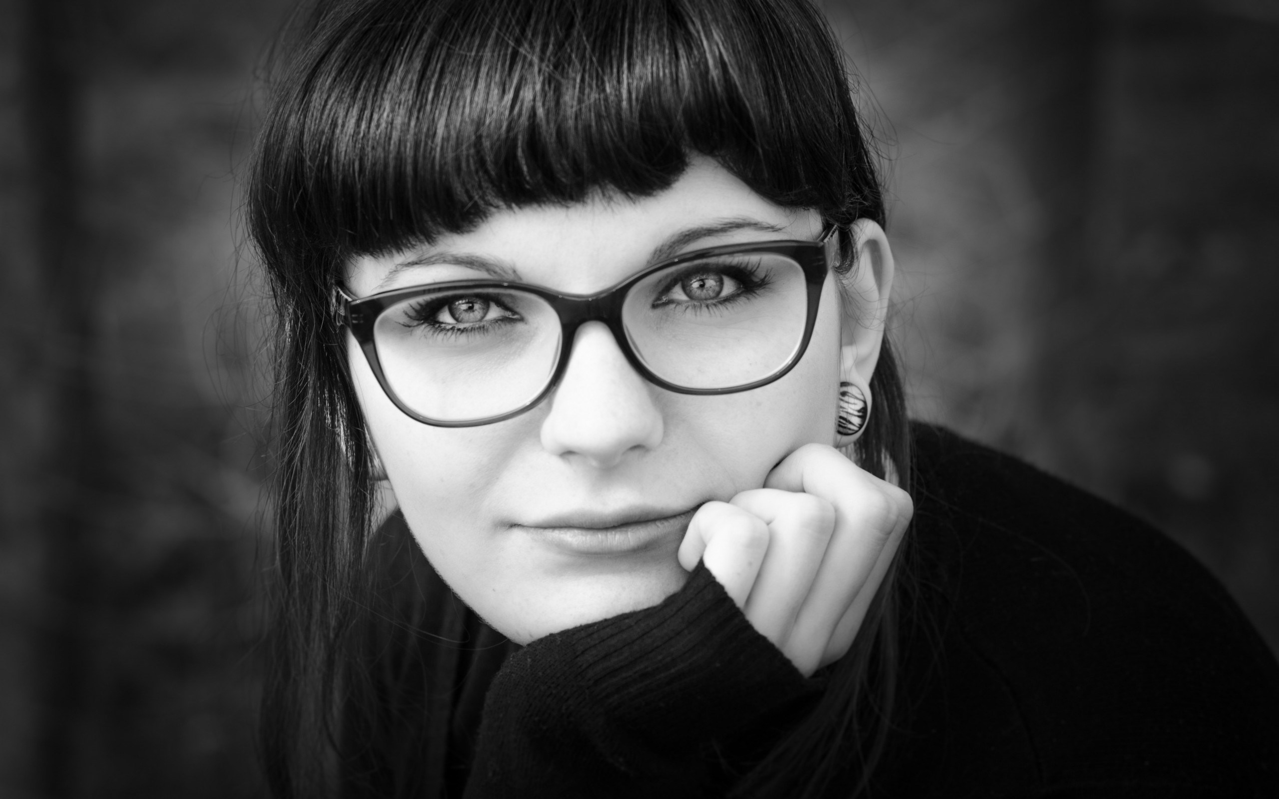 Woman with glasses resting her chin on her hand HD Wallpaper