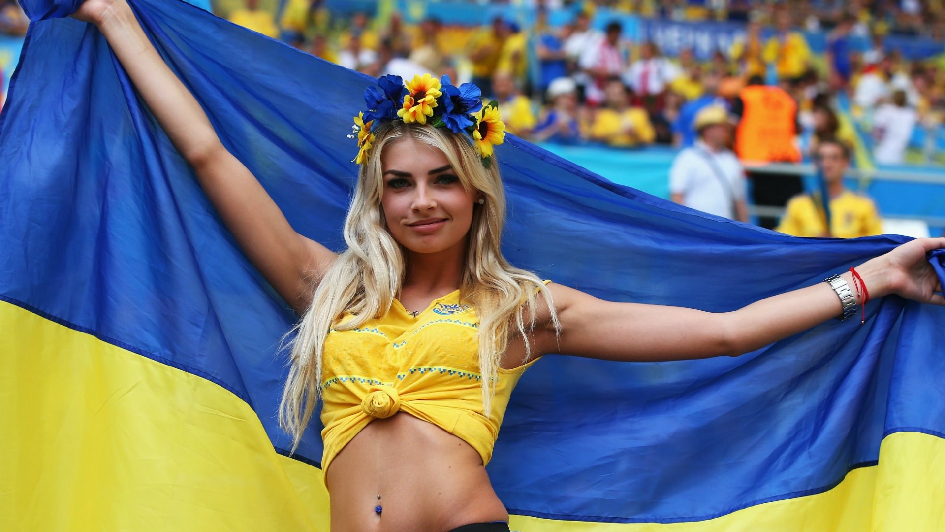Woman holding Ukrainian flag at a sporting event HD Wallpaper