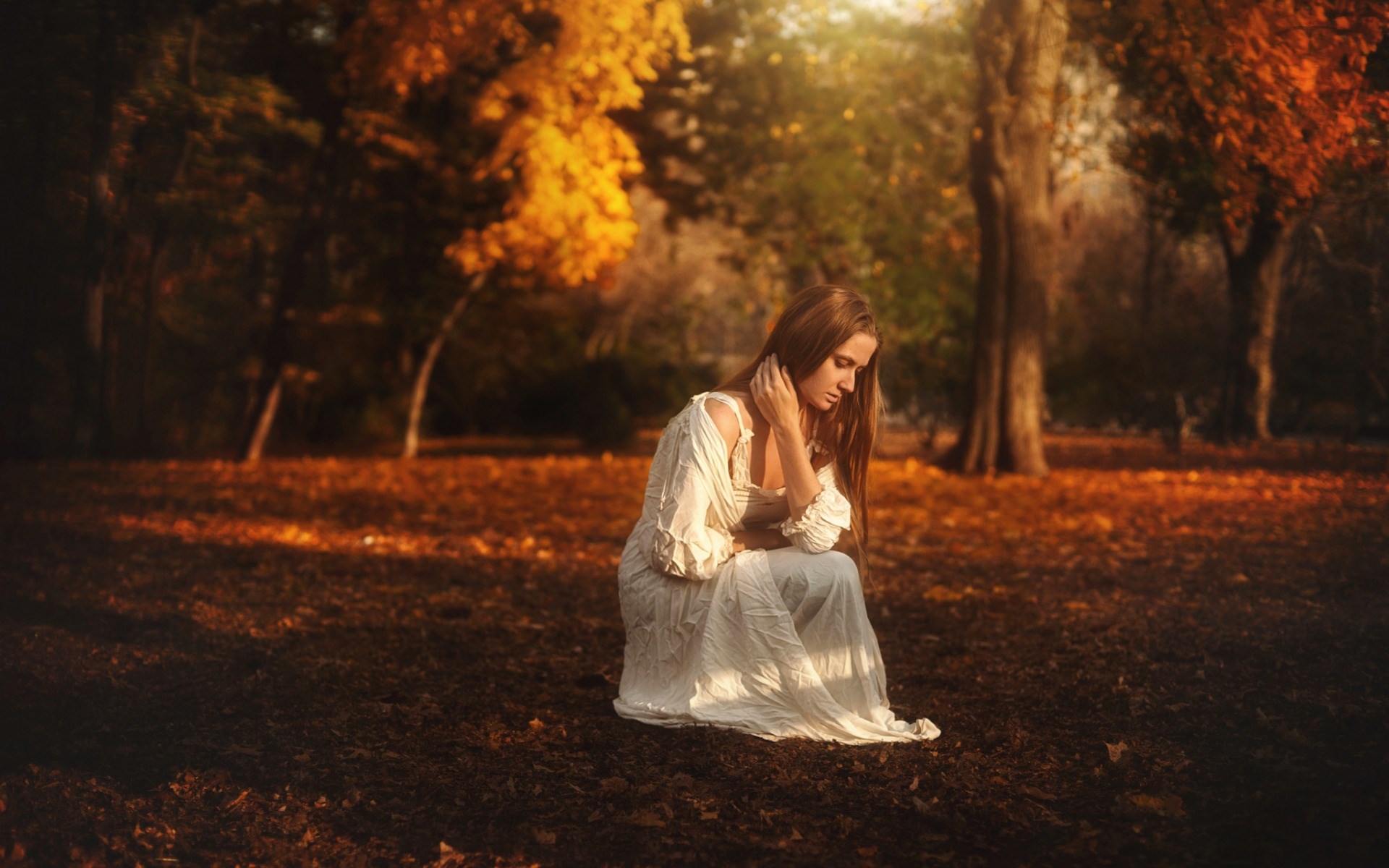 Woman in white dress sitting in autumn park HD Wallpaper