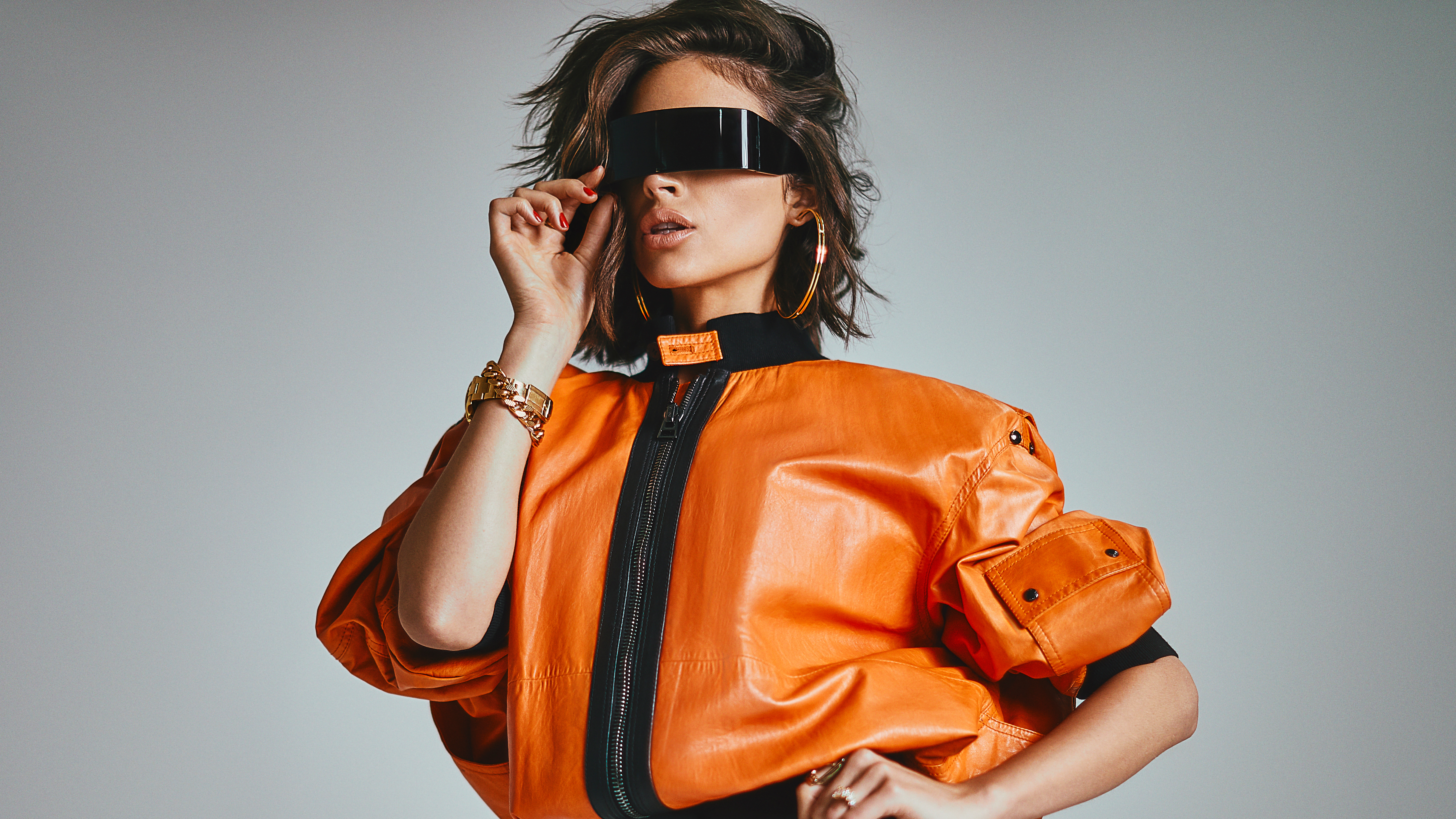 Olivia Culpo wearing futuristic sunglasses and orange jacket HD Wallpaper