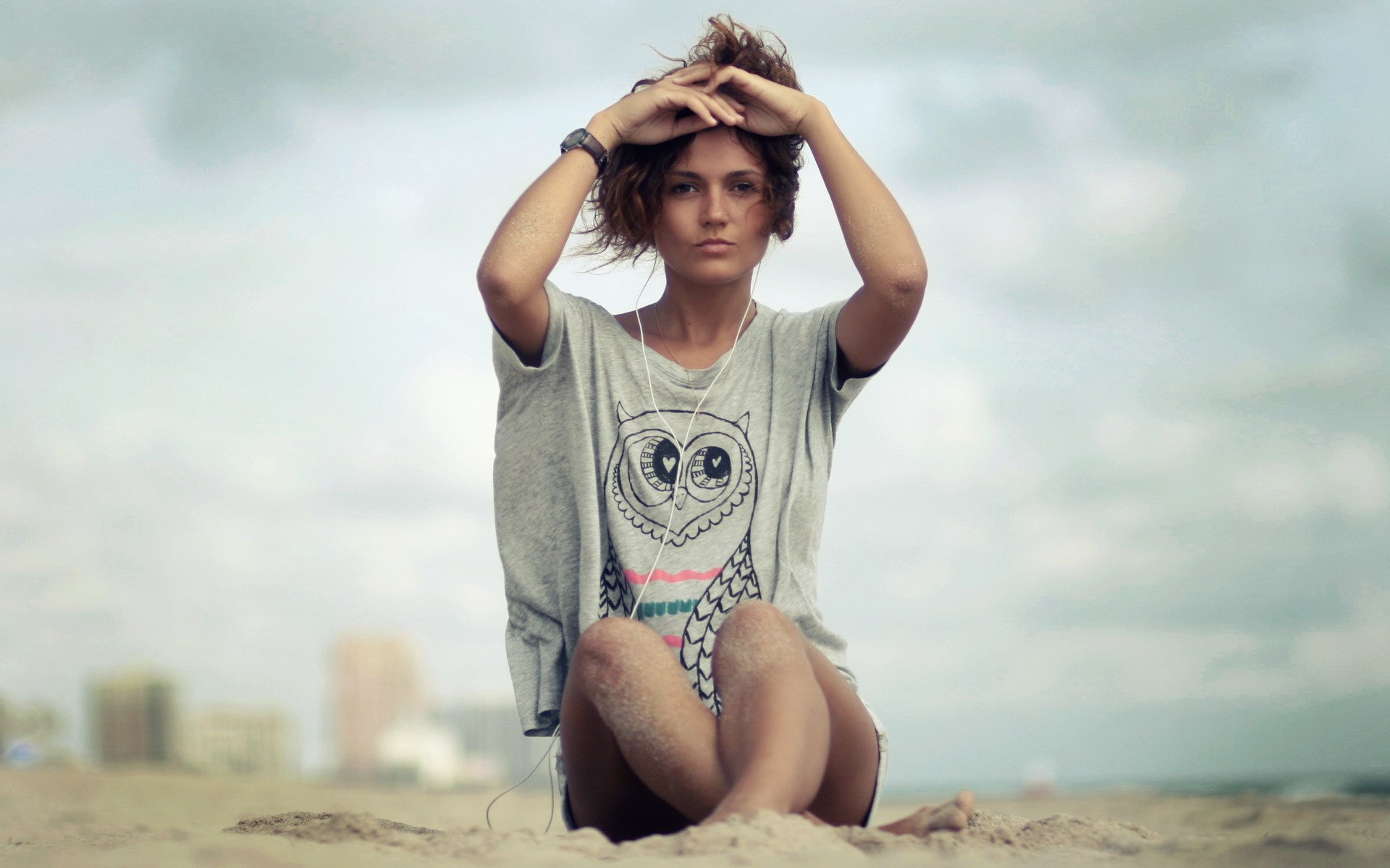Woman sitting on a beach with headphones HD Wallpaper