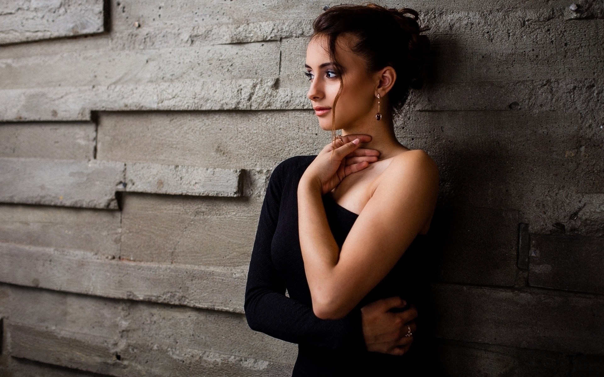 Woman in black dress leaning against a textured wall HD Wallpaper