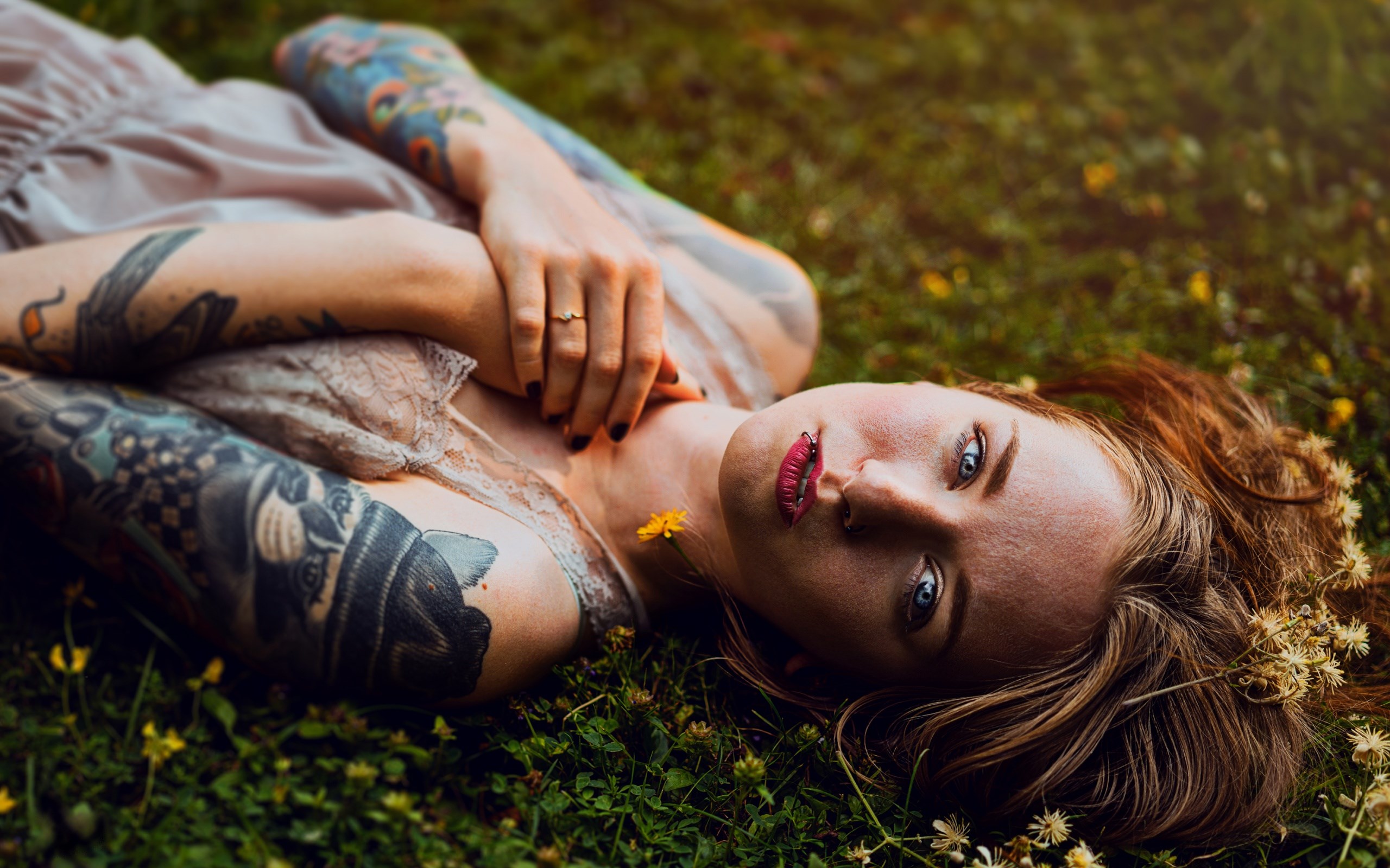 Woman with tattoos lying in grass HD Wallpaper