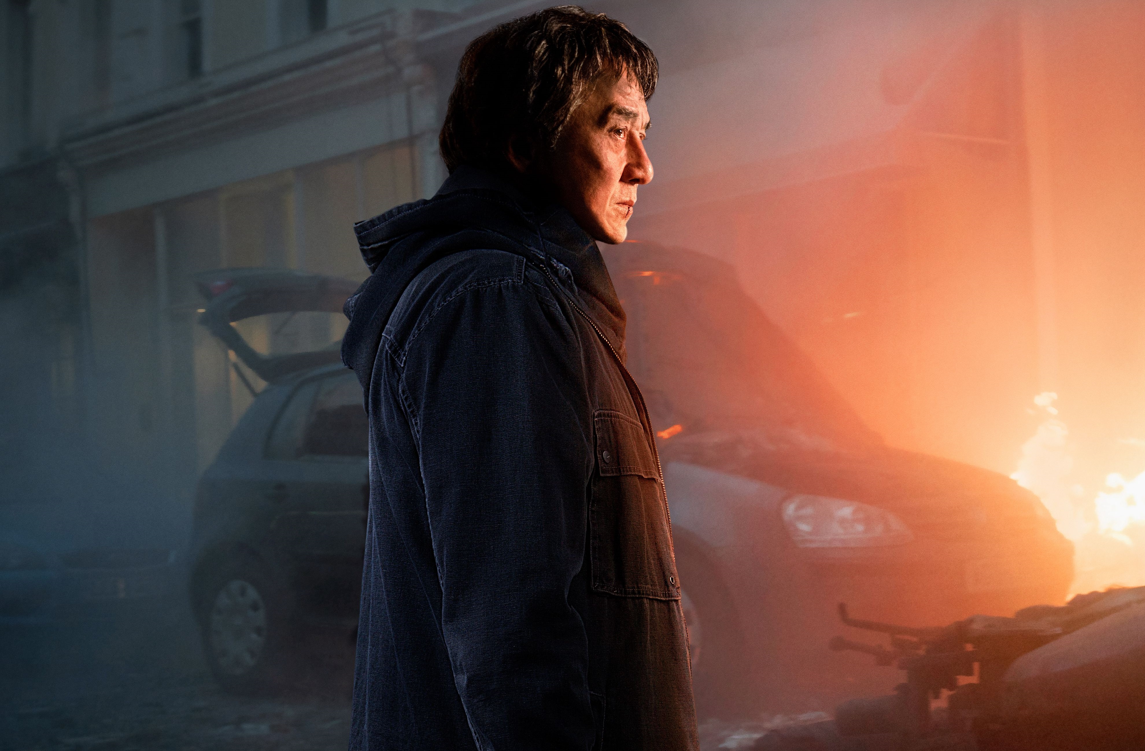 Jackie Chan in a scene with a burning car HD Wallpaper