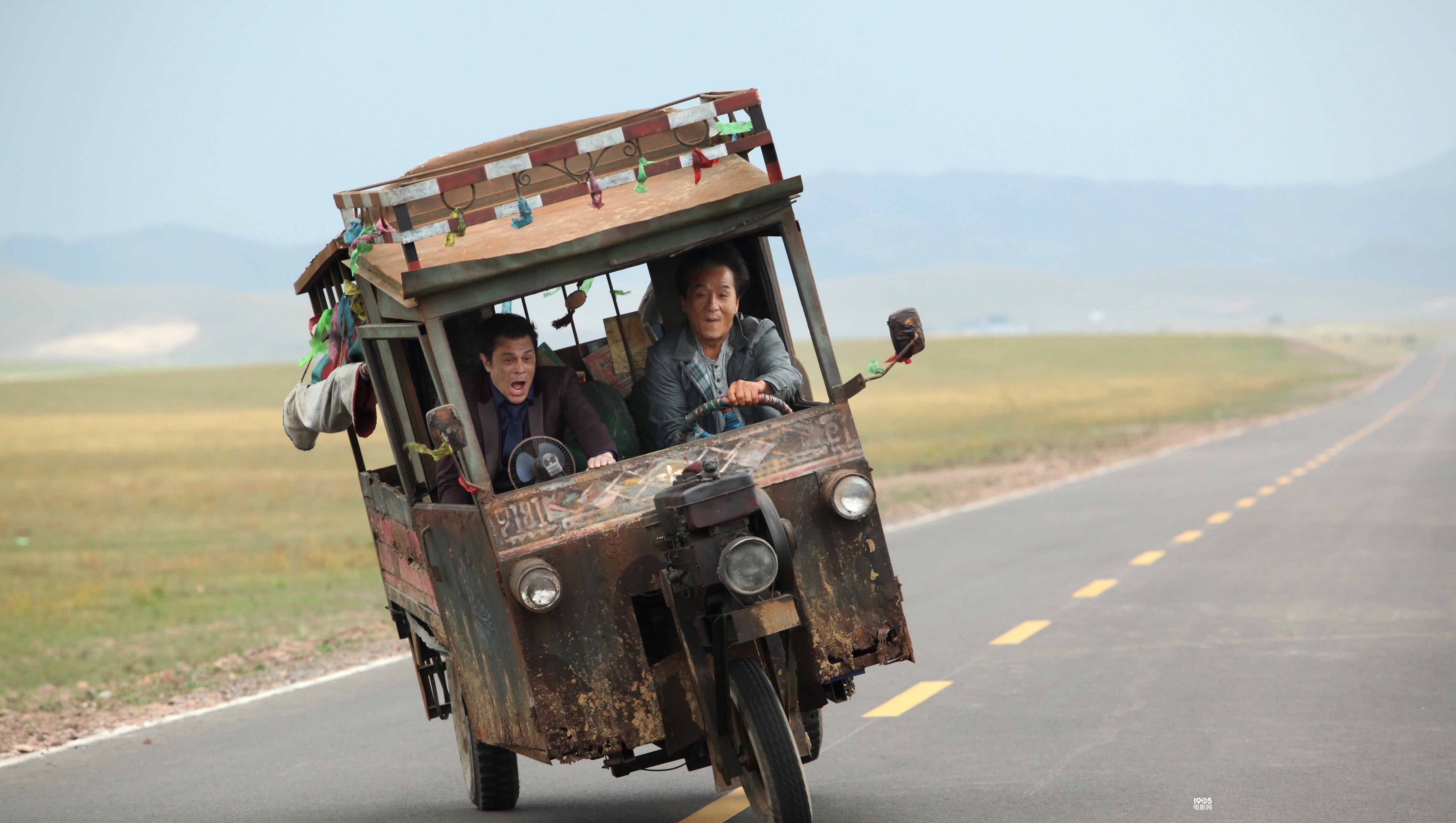 Jackie Chan in a rickety vehicle on a road HD Wallpaper