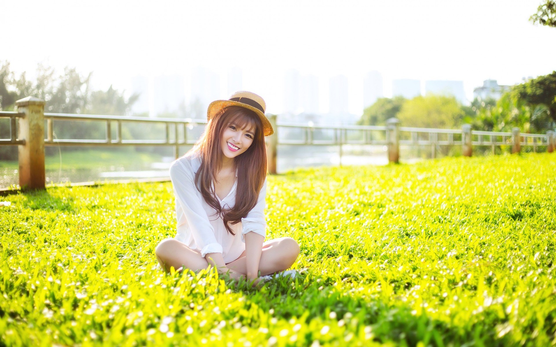 Young woman sitting on grass in a park HD Wallpaper