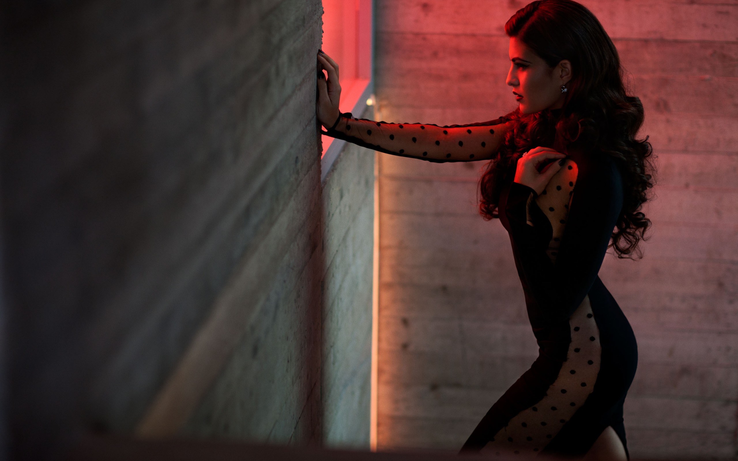 Woman in black dress leaning against concrete wall HD Wallpaper
