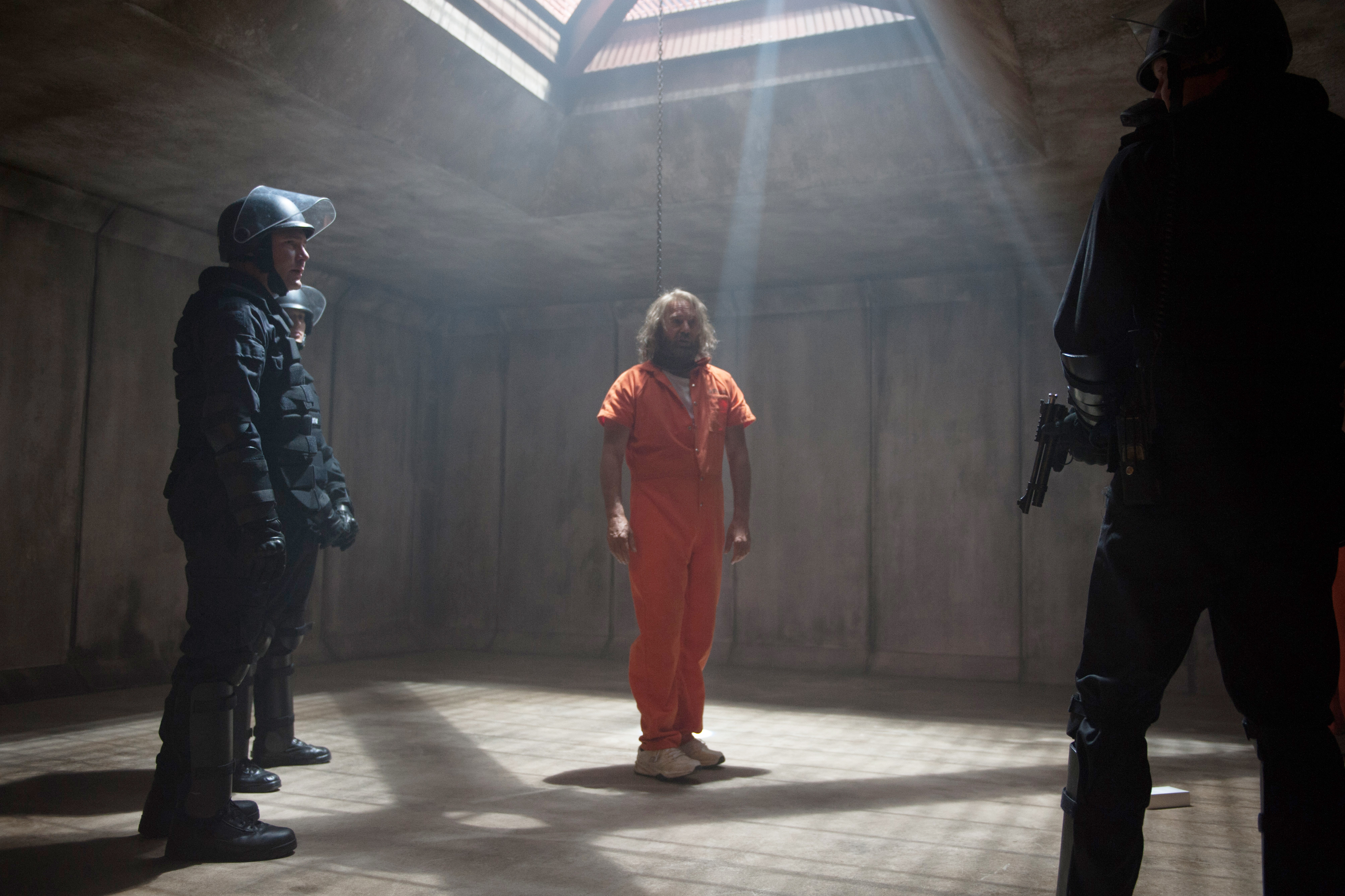 Kevin Costner in an orange jumpsuit with guards HD Wallpaper
