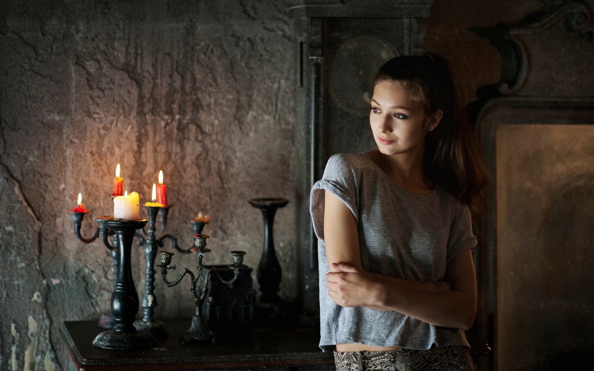 Young woman by candelabra in dark room HD Wallpaper