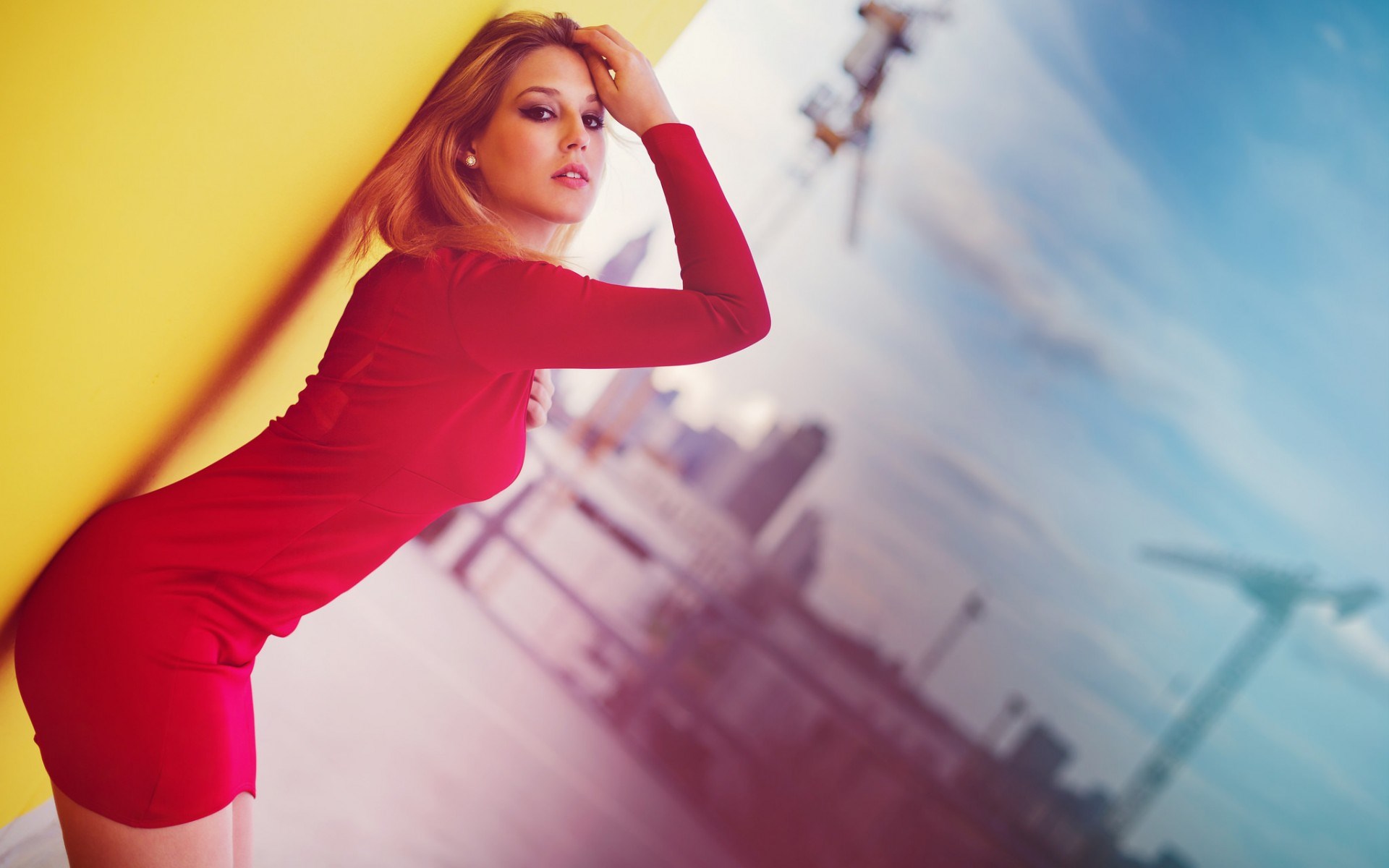 Woman in red dress leaning against yellow wall HD Wallpaper