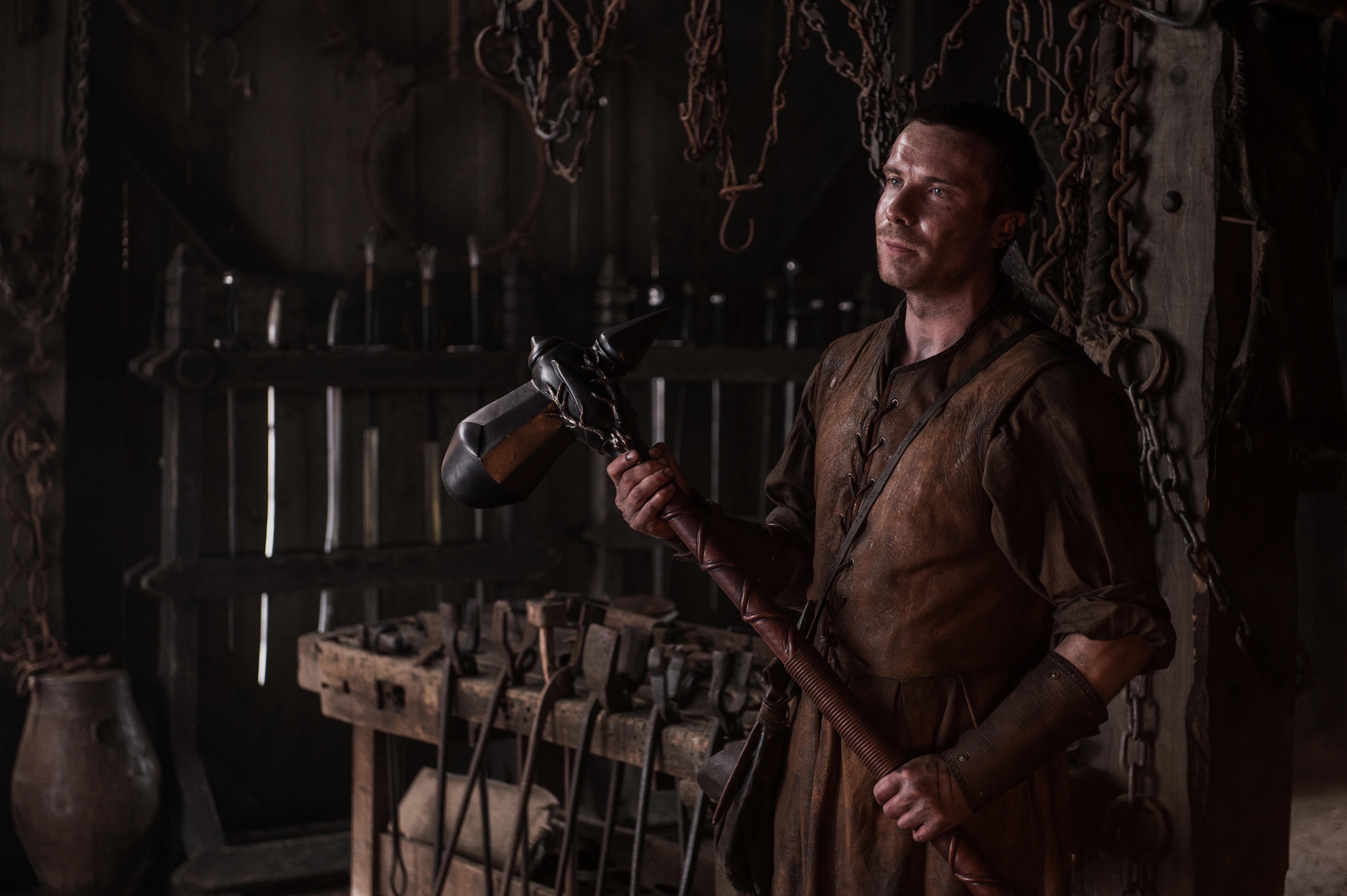 Joe Dempsie holding a hammer in a workshop HD Wallpaper