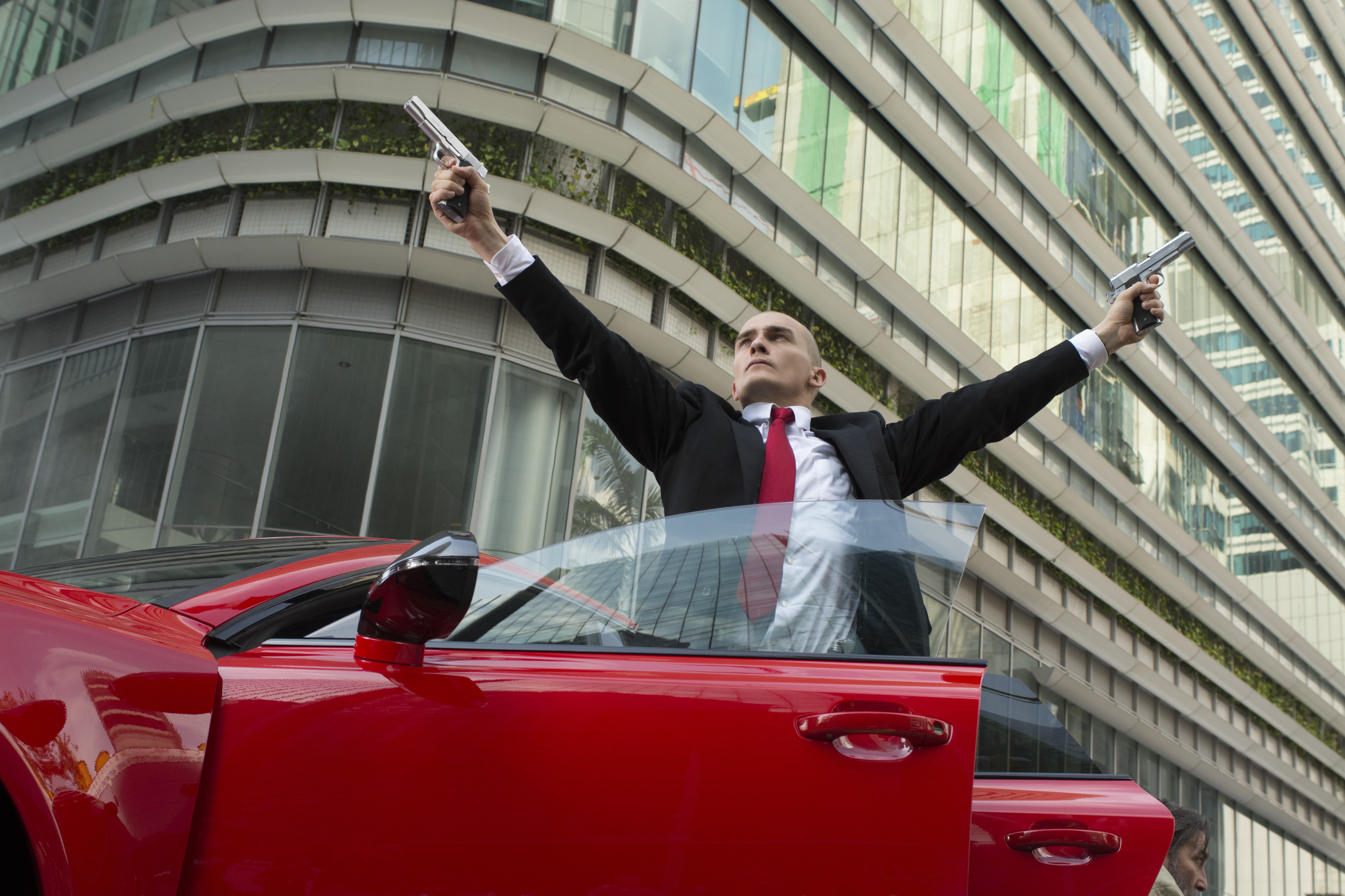Rupert Friend as Agent 47 in a red car HD Wallpaper