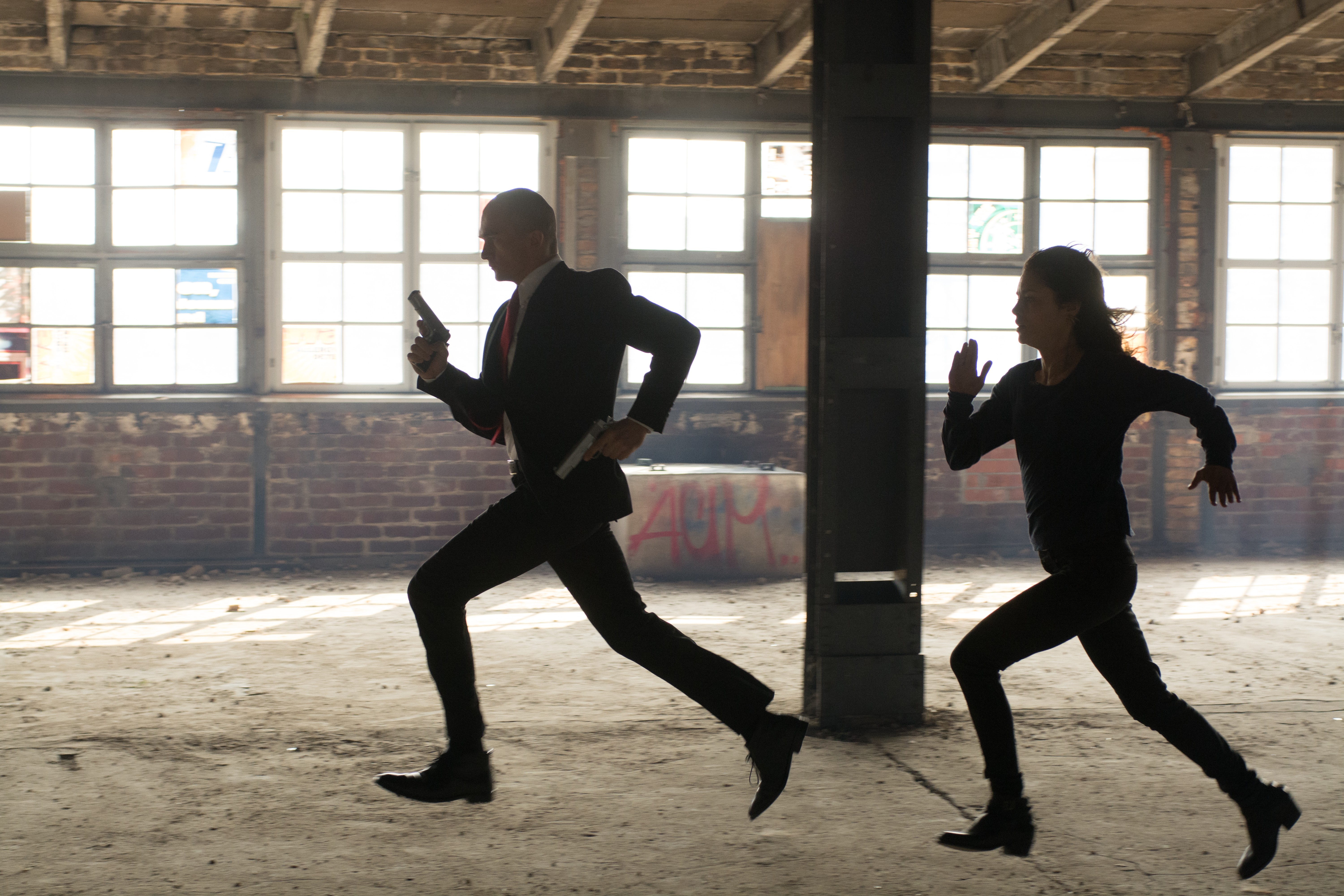 Rupert Friend in a suit running with a gun HD Wallpaper