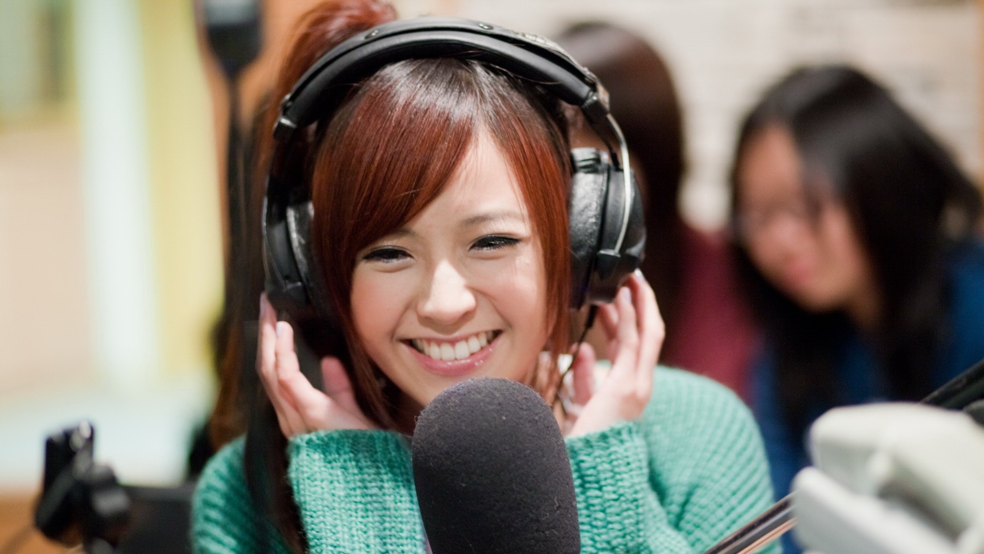 Woman wearing headphones and speaking into a microphone HD Wallpaper