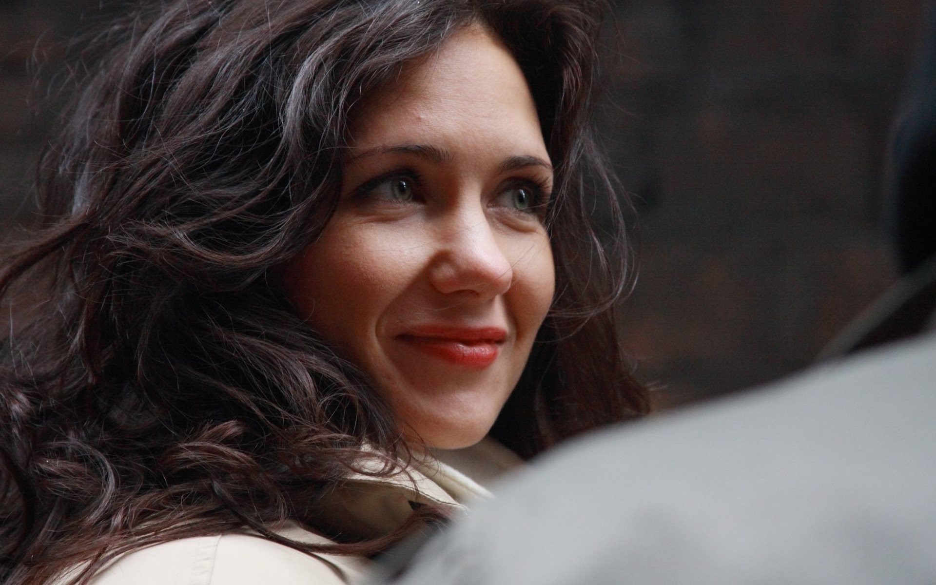 Woman with dark wavy hair smiling HD Wallpaper