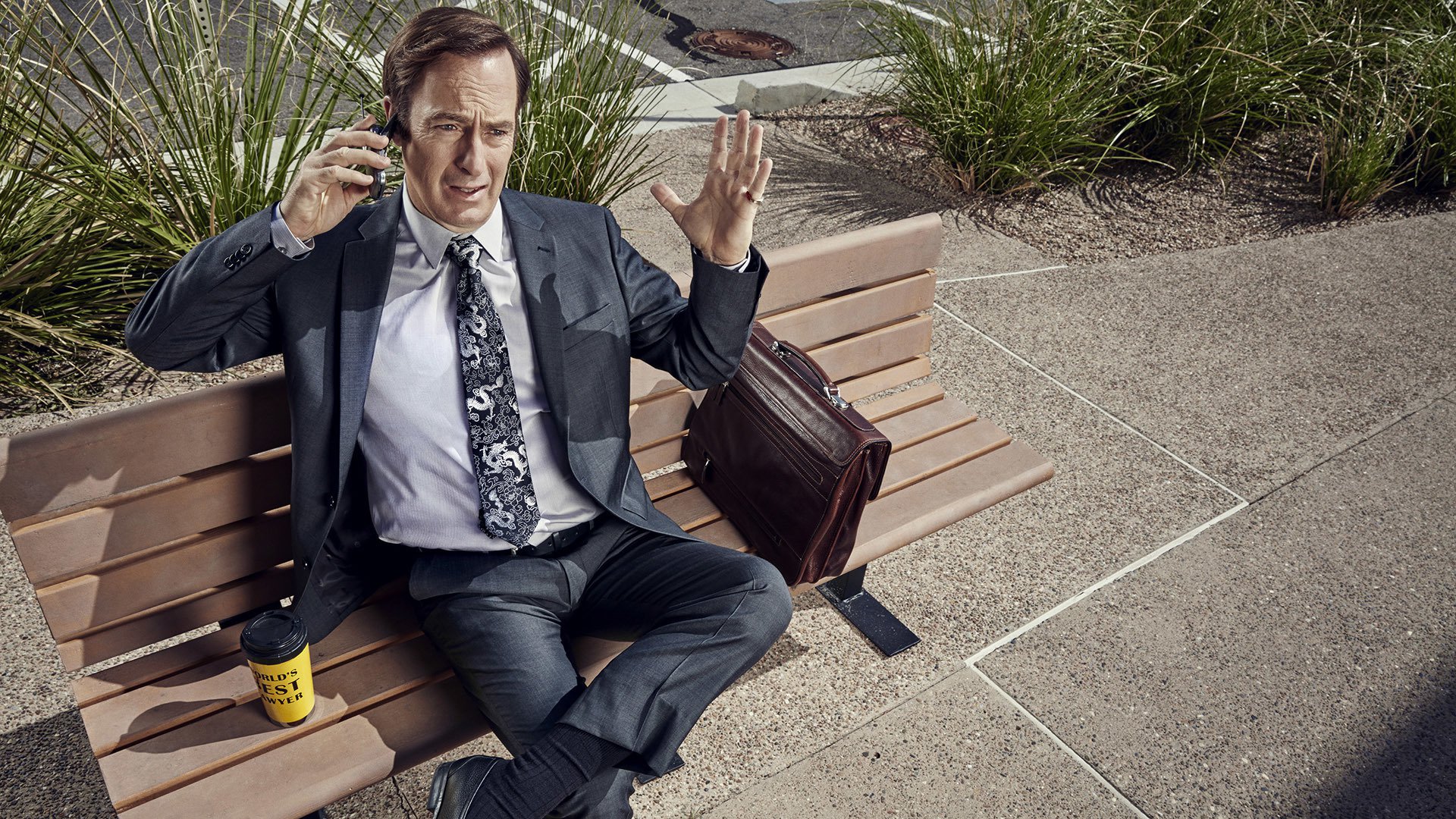 Bob Odenkirk sitting on a bench with a briefcase and coffee HD Wallpaper