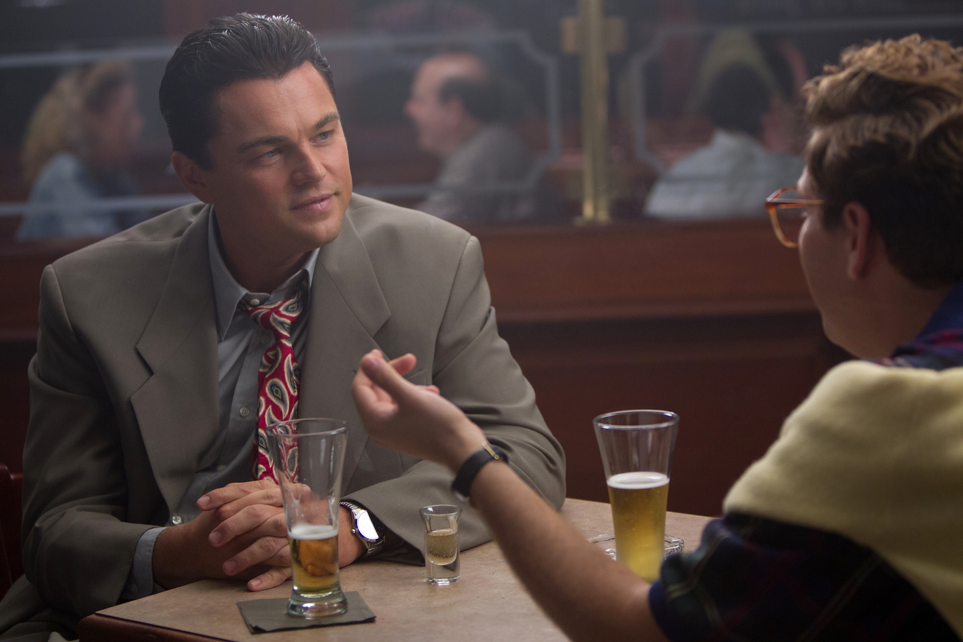Leonardo DiCaprio and Jonah Hill at a table with drinks HD Wallpaper