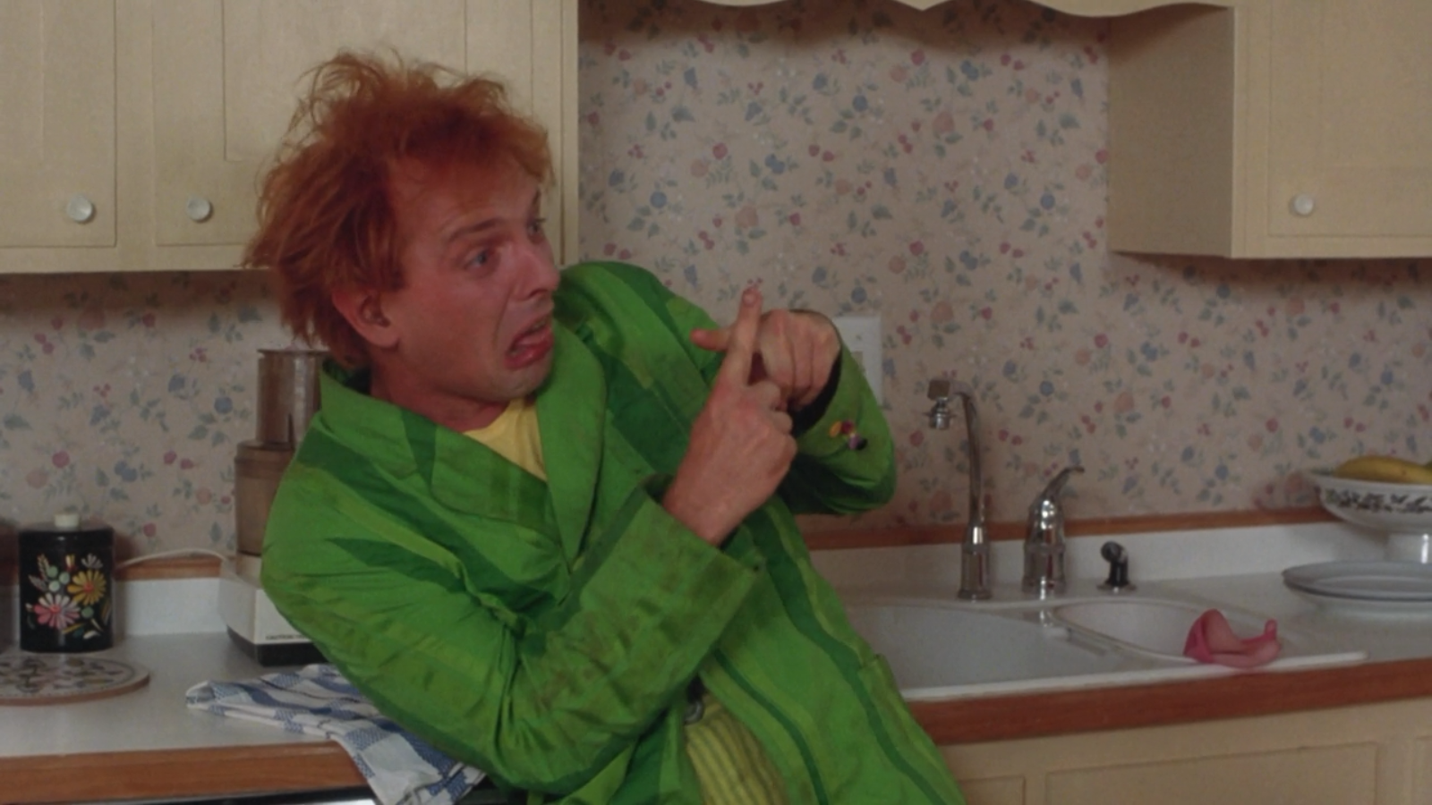 Rik Mayall in a green robe in a kitchen HD Wallpaper