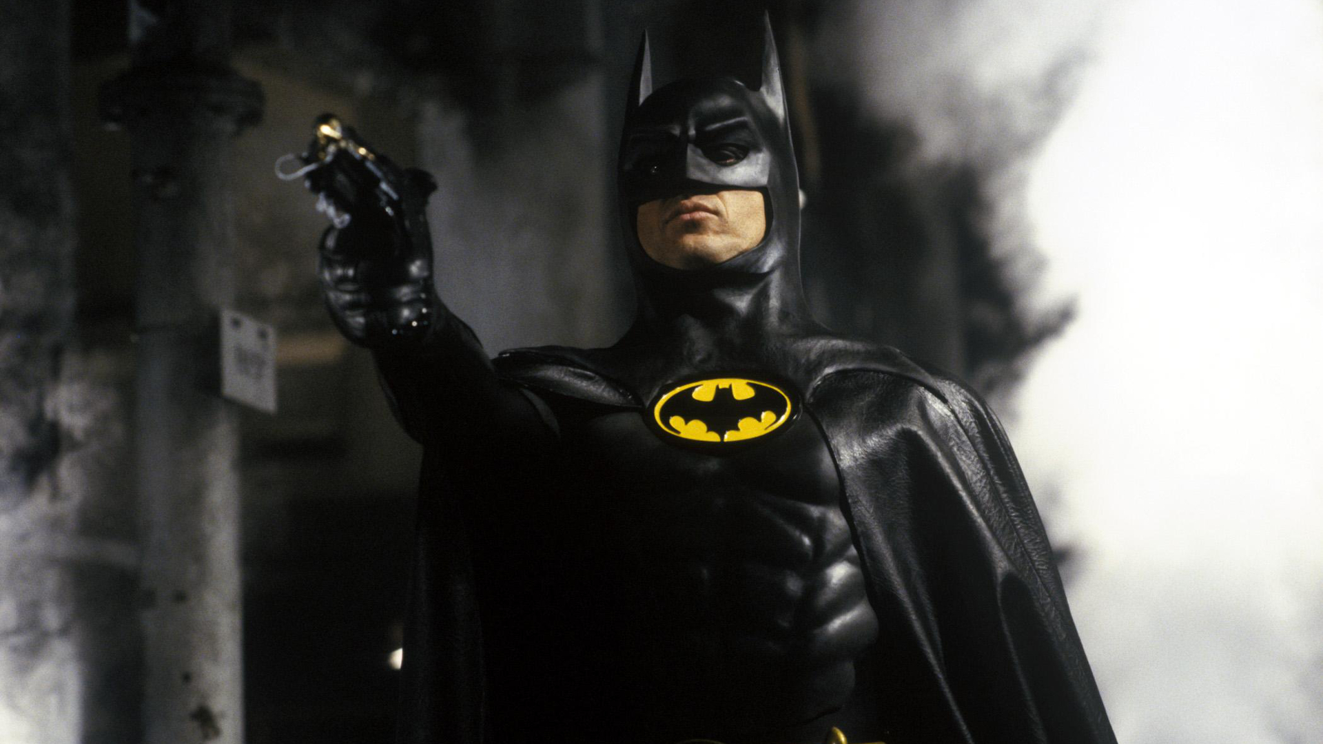 Michael Keaton as Batman holding a grappling gun HD Wallpaper