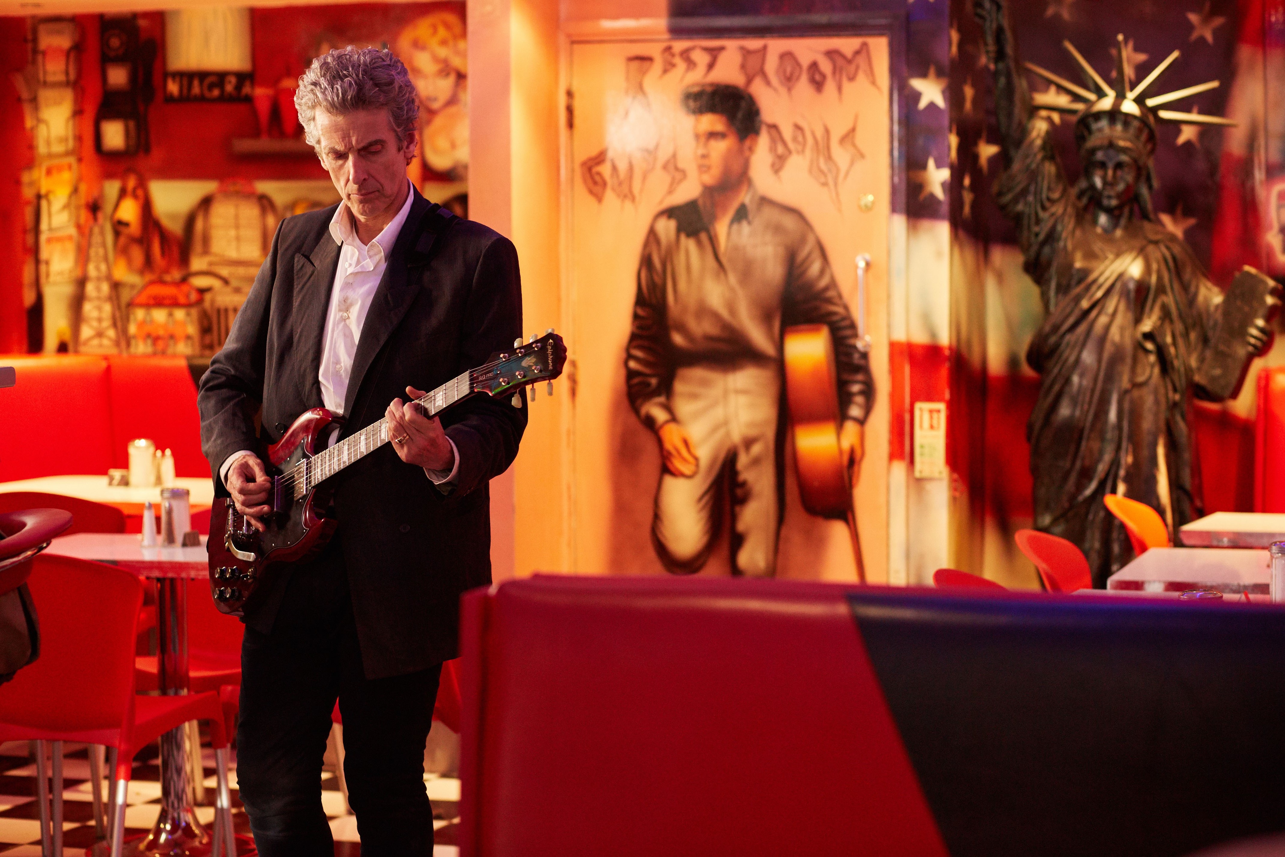 Peter Capaldi playing guitar in a diner HD Wallpaper