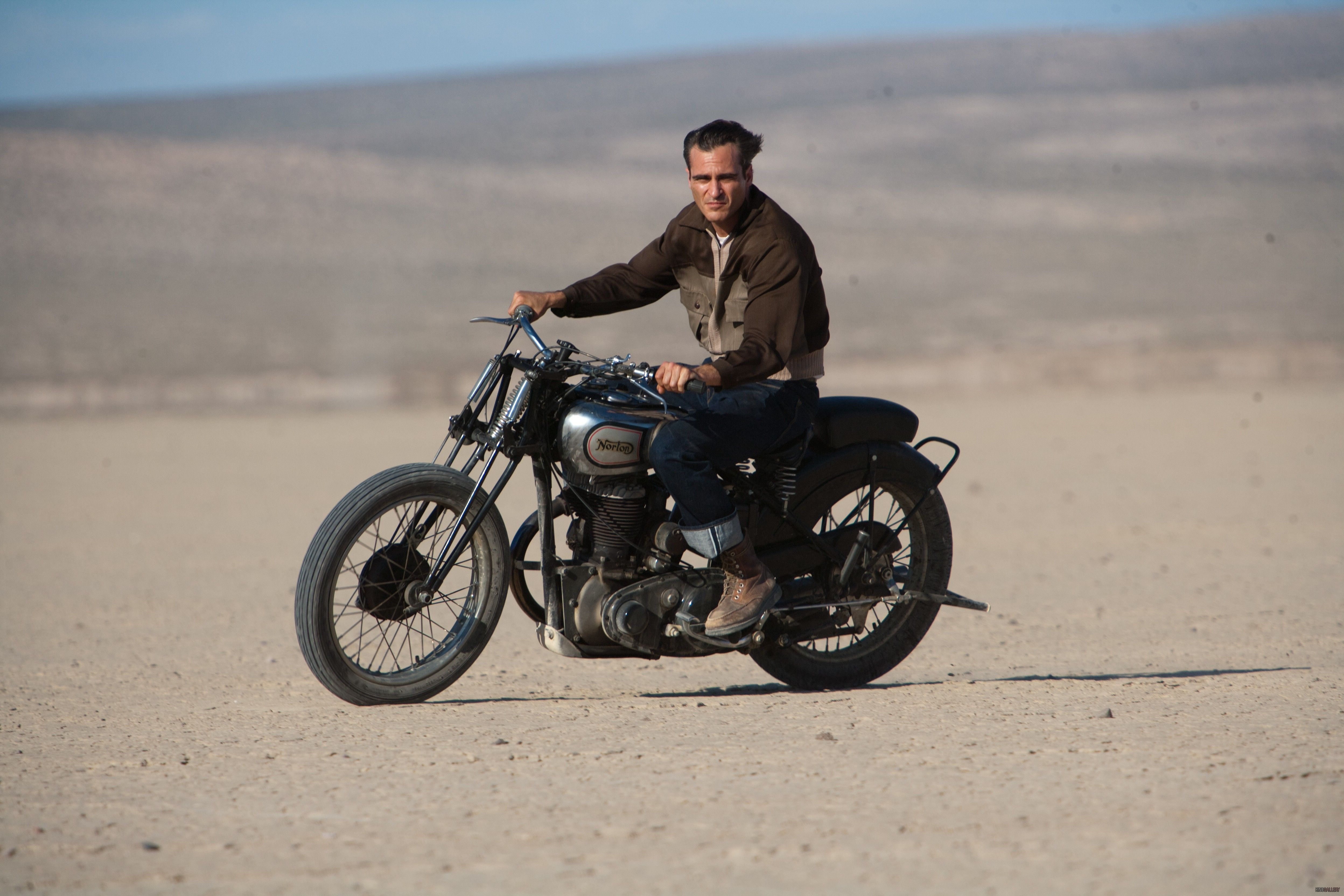 Joaquin Phoenix riding a motorcycle in a desert HD Wallpaper