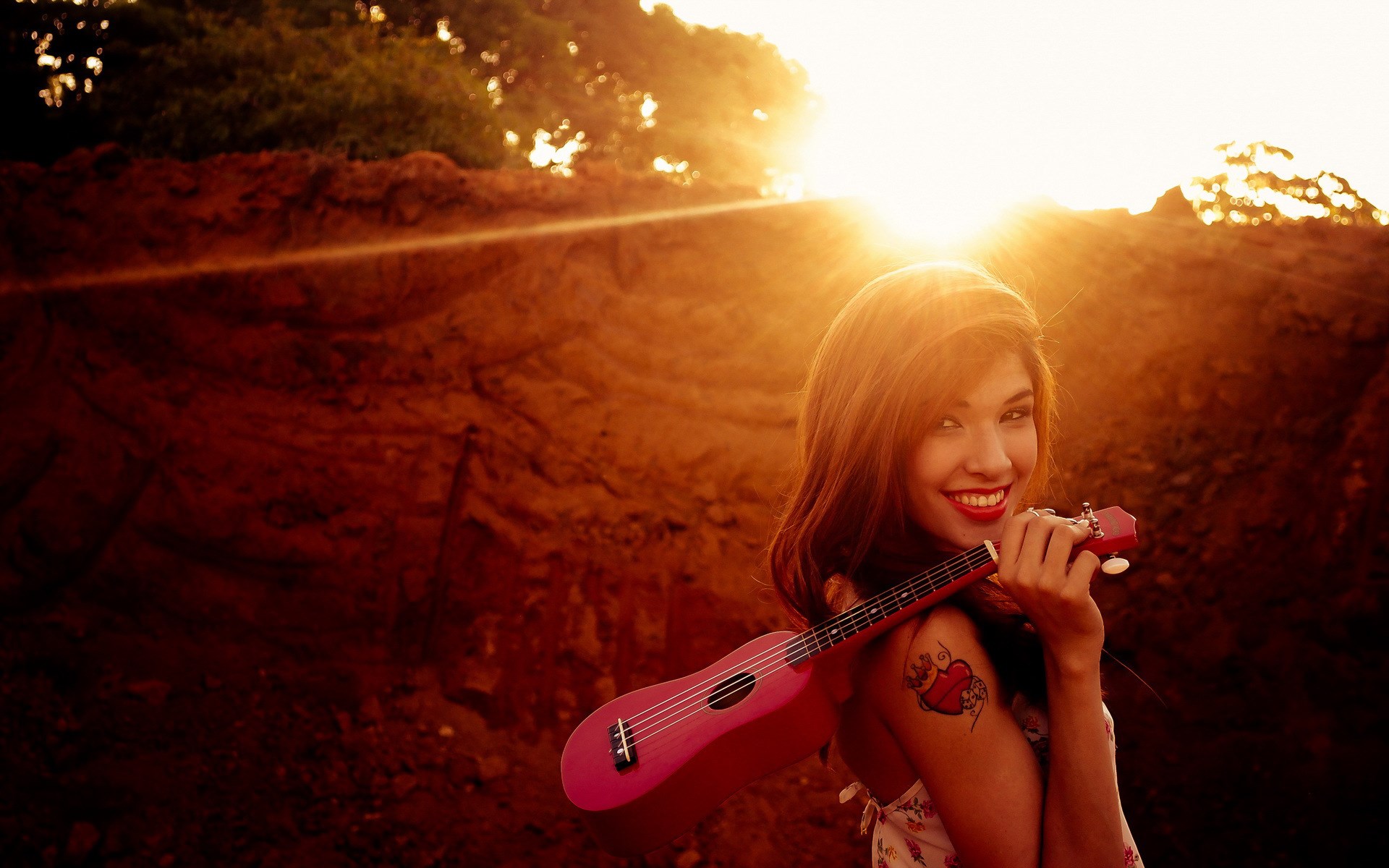Woman holding a pink ukulele at sunset HD Wallpaper