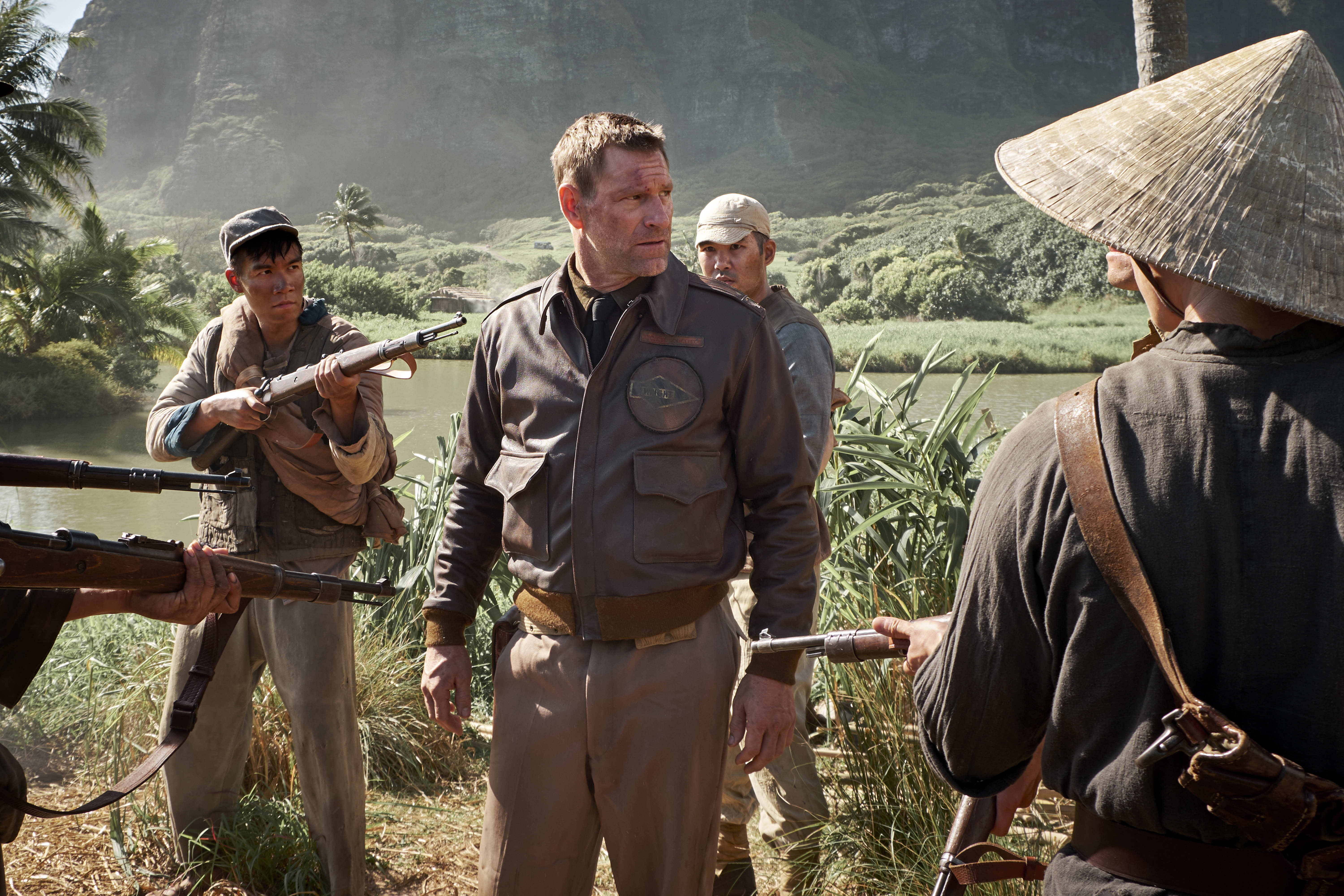 Aaron Eckhart in a jungle setting with soldiers HD Wallpaper