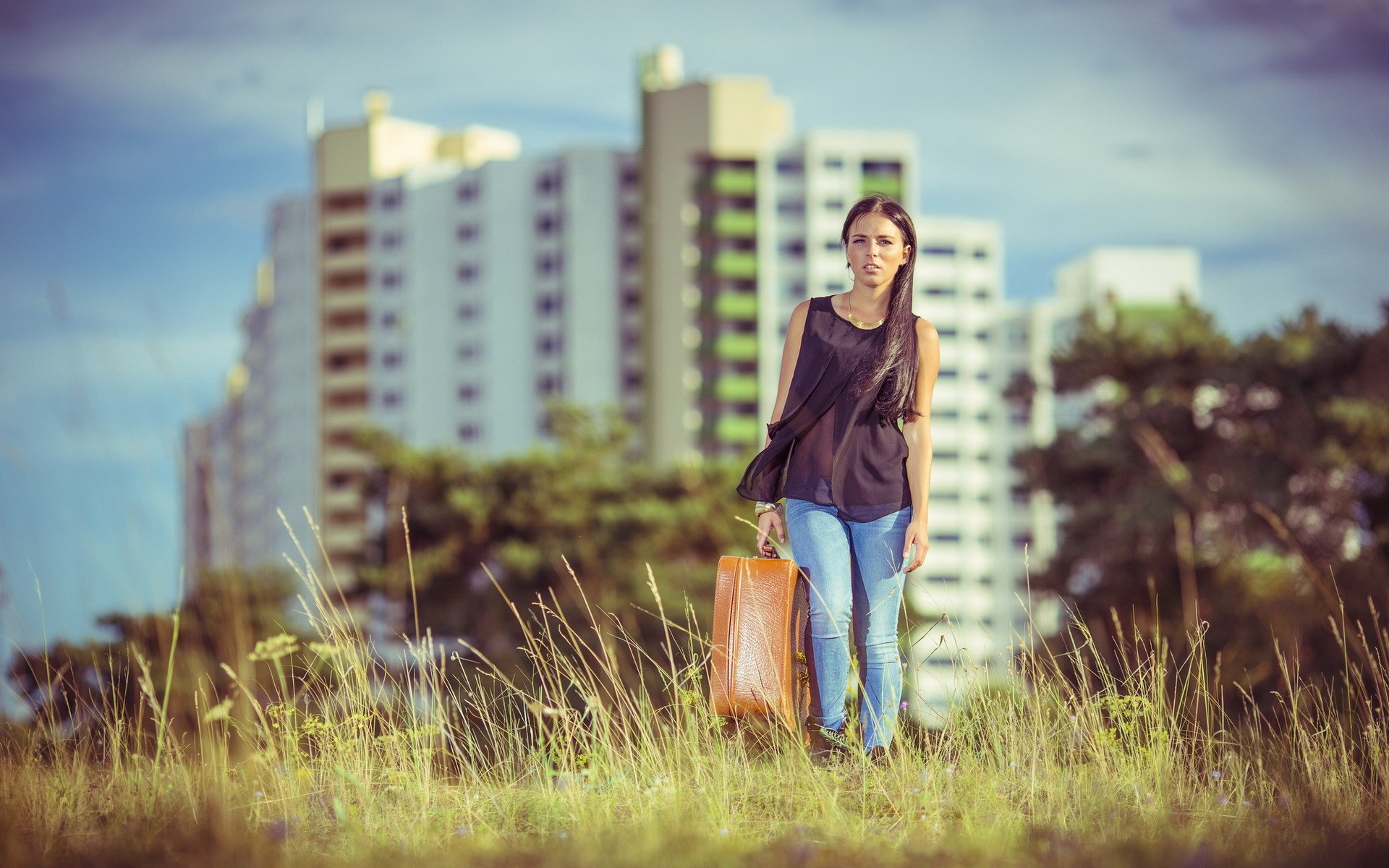 Woman with suitcase in front of apartment buildings HD Wallpaper